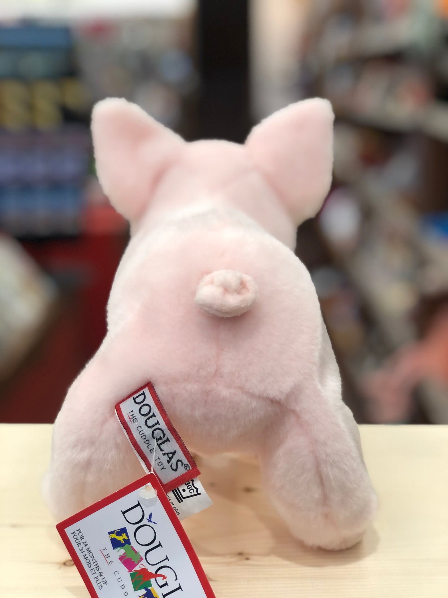 Soft pink Douglas Betina pig plush toy with large ears and curly tail, shown from behind with brand tags visible