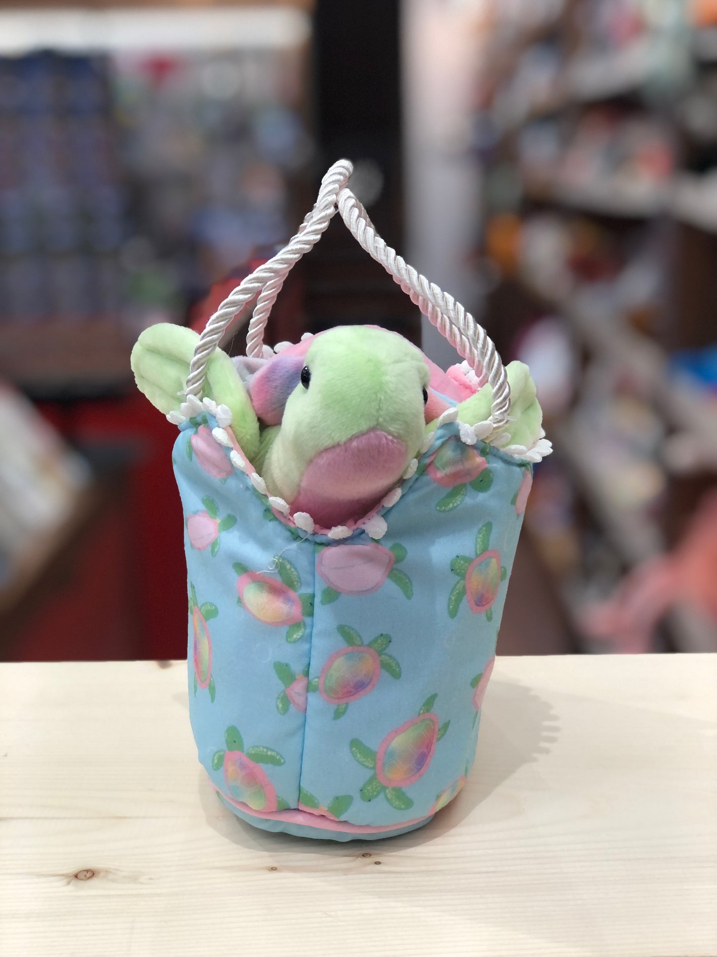Colorful sea turtle plush toy peeking out of blue handbag with turtle pattern and rope handles, perfect for summer beach fun