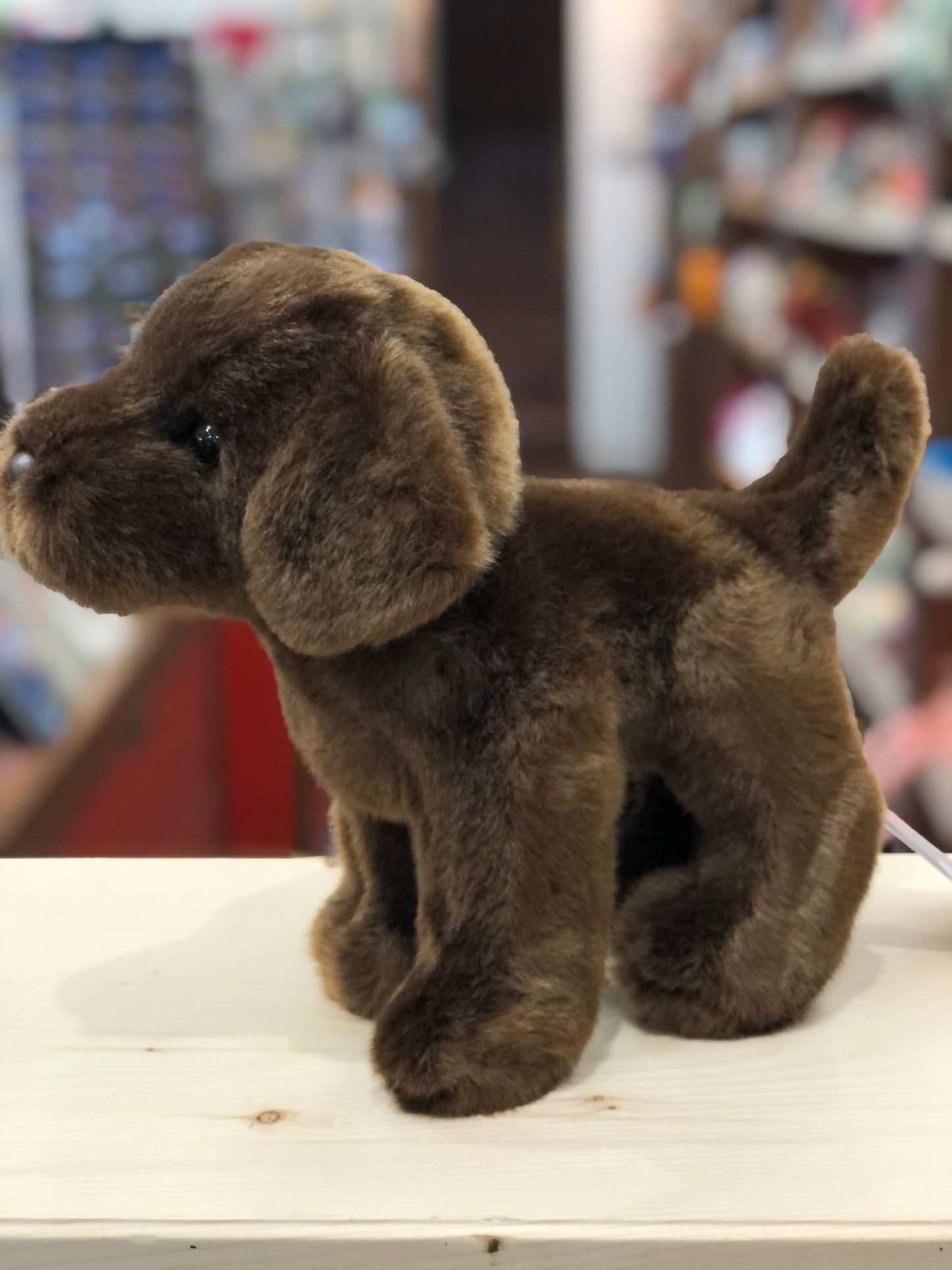 Soft, cuddly chocolate Labrador plush toy standing on display, with floppy ears and expressive eyes
