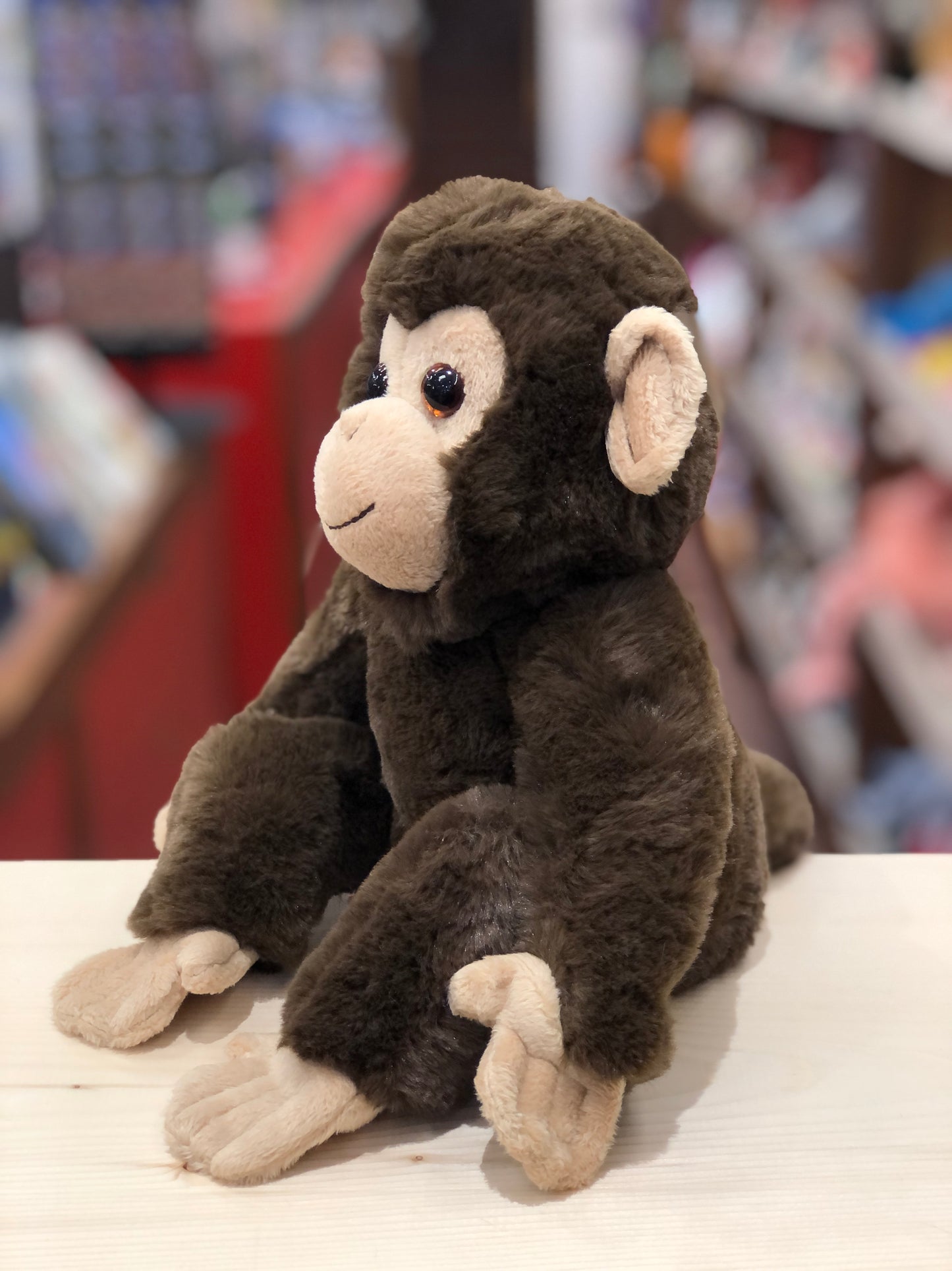 Mikie soft monkey plush toy with brown fur, tan accents, and a mischievous smile, sitting on display in a store