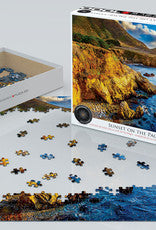 Coastal puzzle box featuring dramatic sunset over rocky Pacific shoreline, with scattered pieces on table