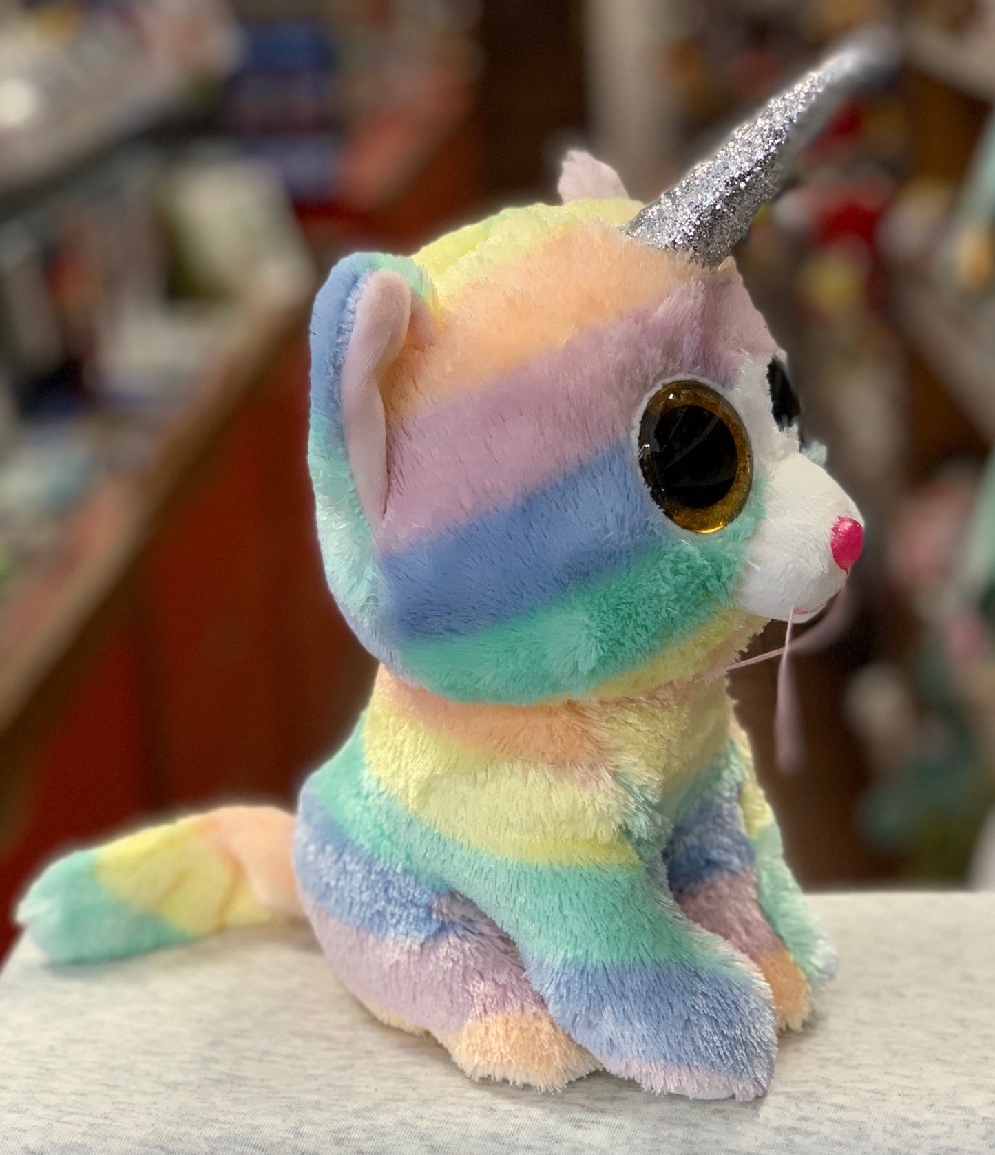 Colorful Ty Beanie Boo unicorn cat plush toy with rainbow fur, glittery horn, and large golden eyes