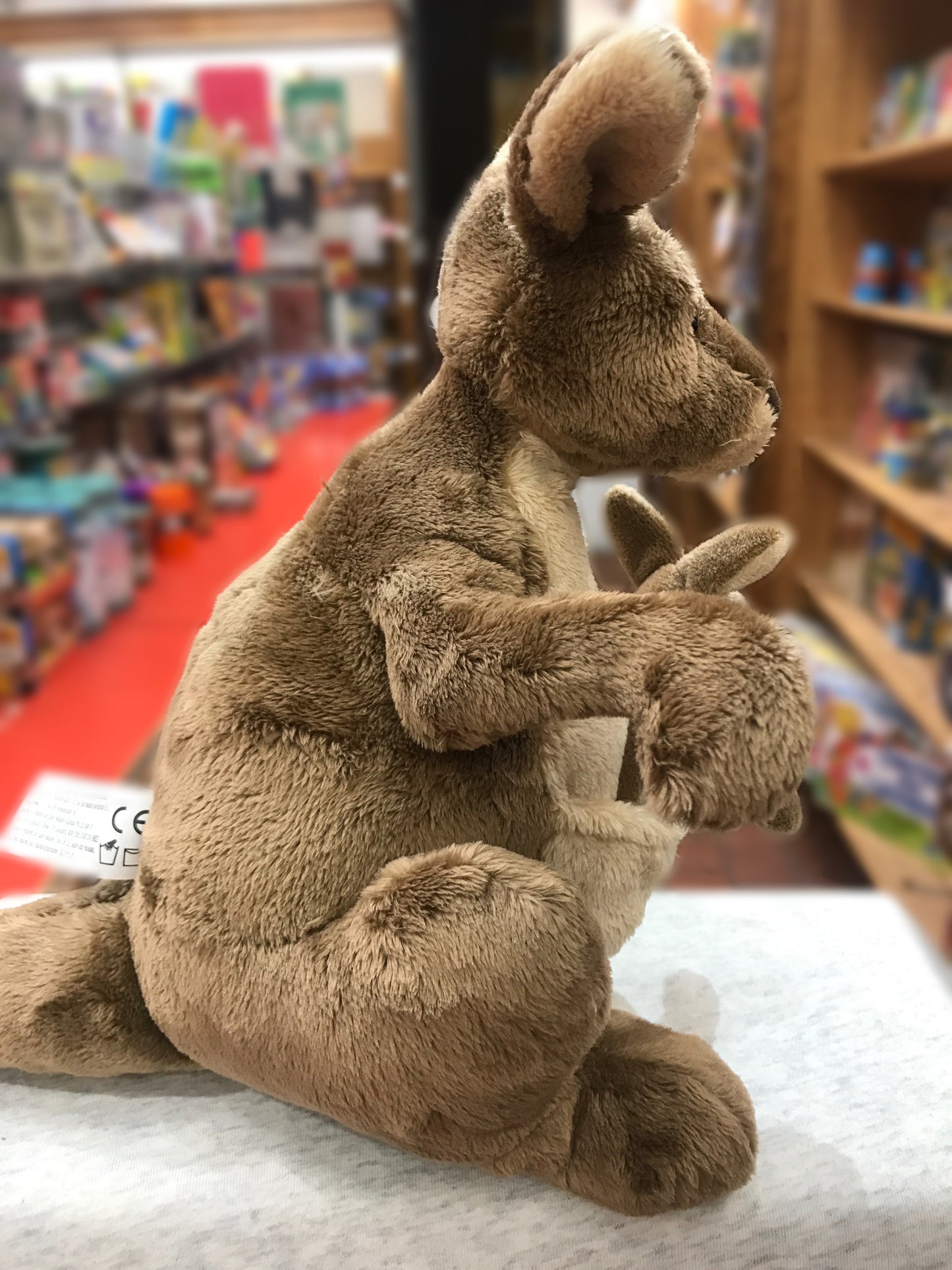 Gund Jirra brown plush kangaroo toy with joey in pouch, sitting on display in toy store
