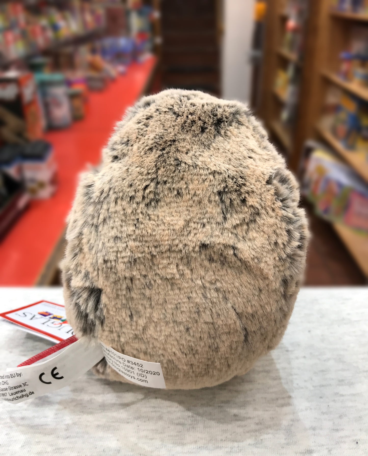 Spunky hedgehog plush toy, 5 inches, soft brown fur, sitting in toy store with red carpet and shelves visible