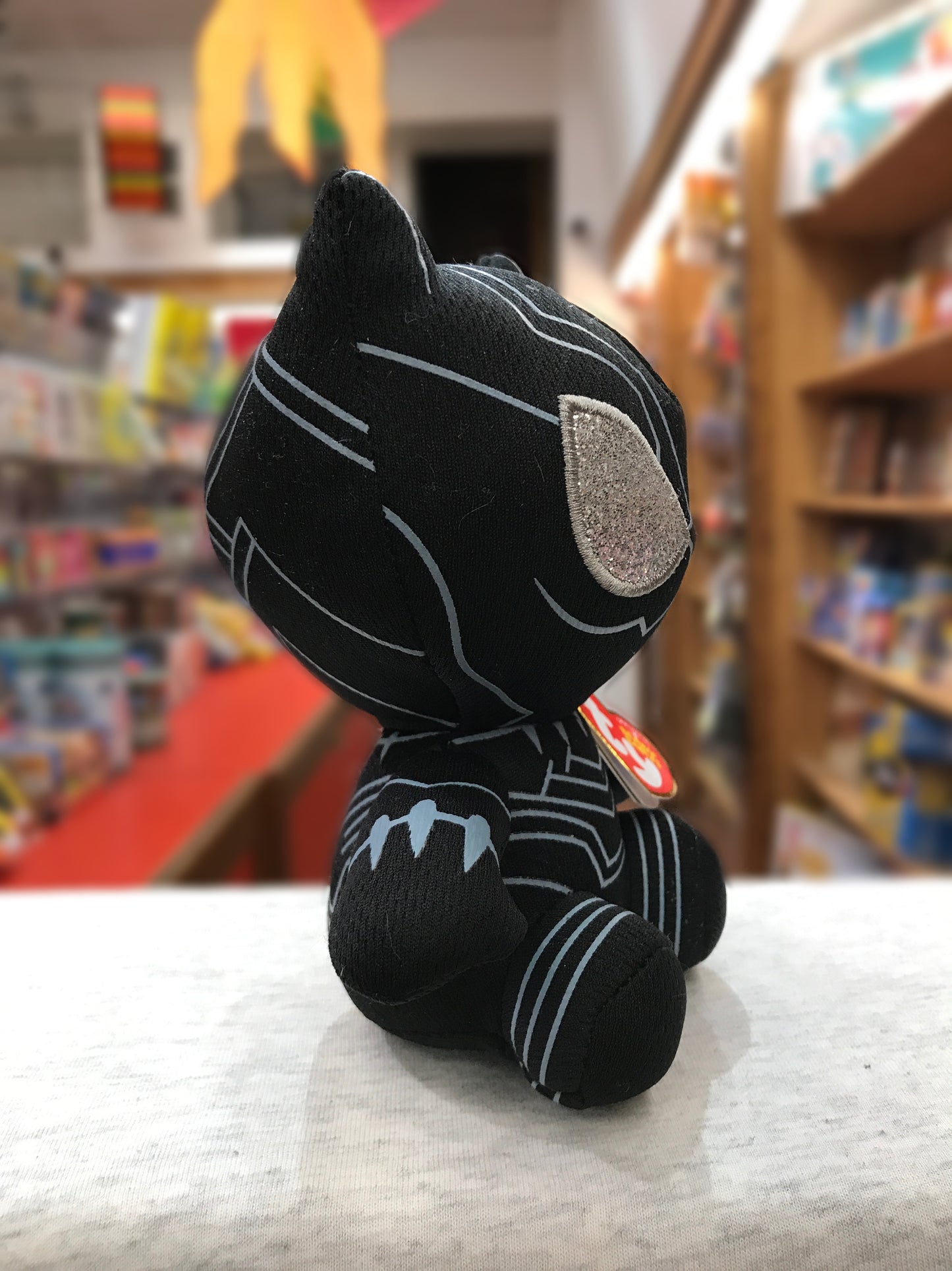 Ty Beanie Baby Black Panther plush toy in bookstore, showcasing Marvel character's iconic suit design and silver ear detail