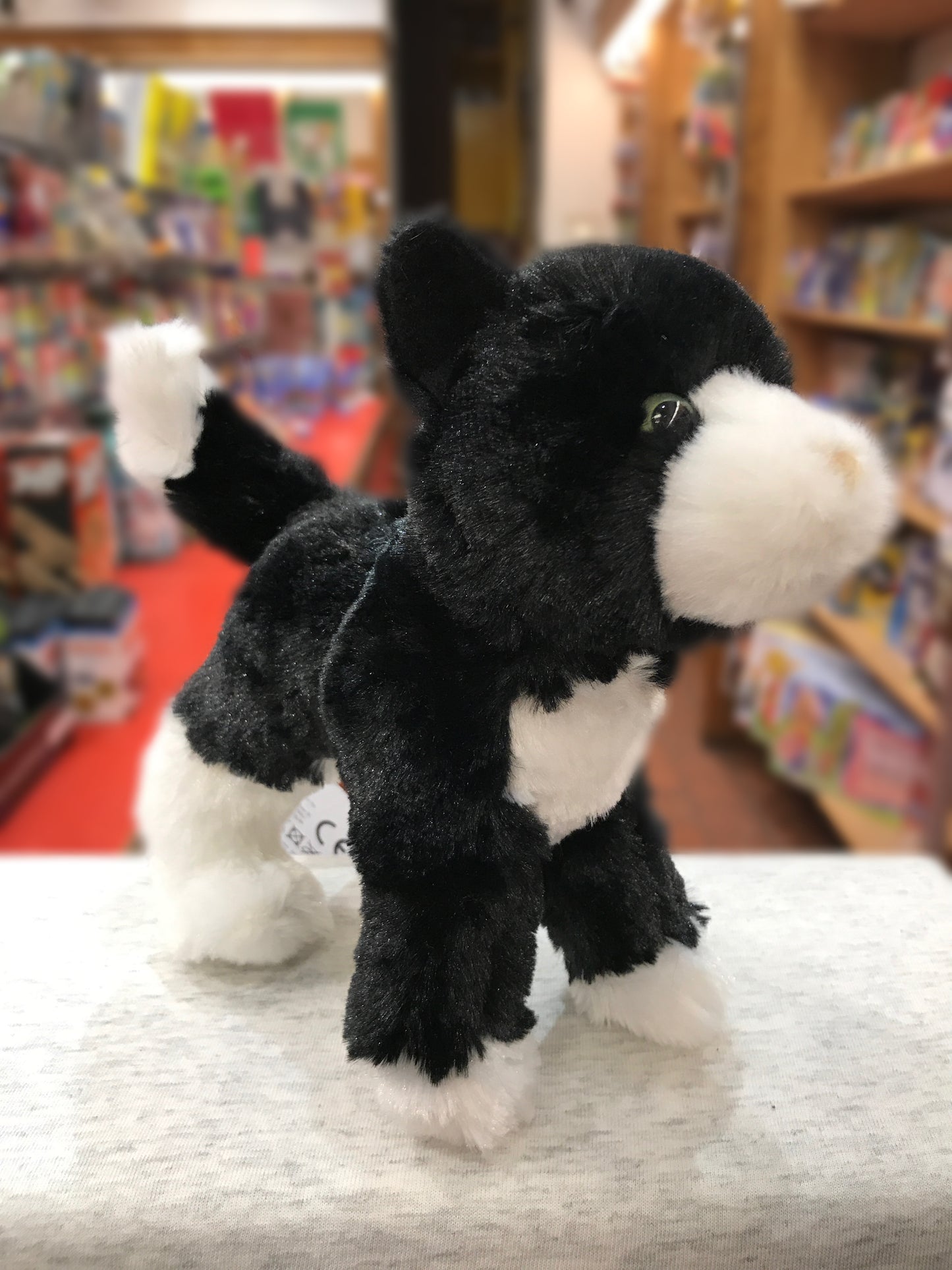 Cute black and white cat plush toy with tuxedo markings standing on display in a toy store