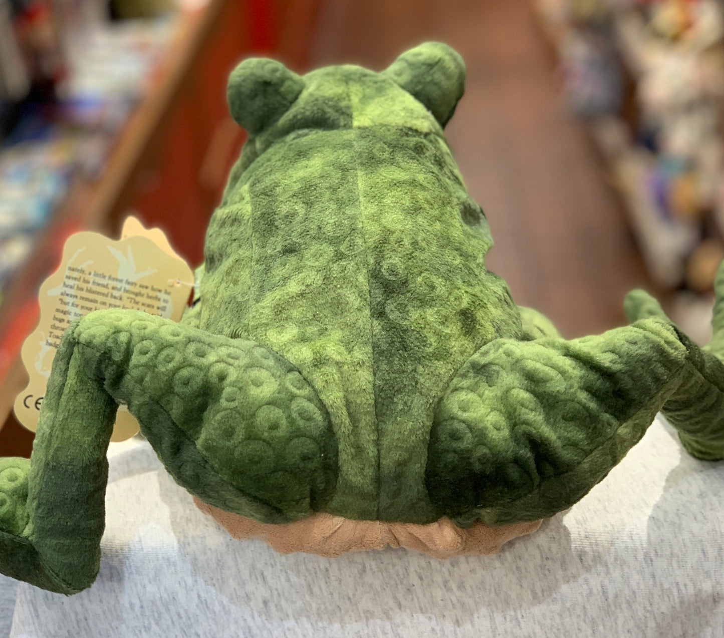Folkmanis Toad Puppet with textured green plush body, wide eyes, and movable limbs, shown from behind on display