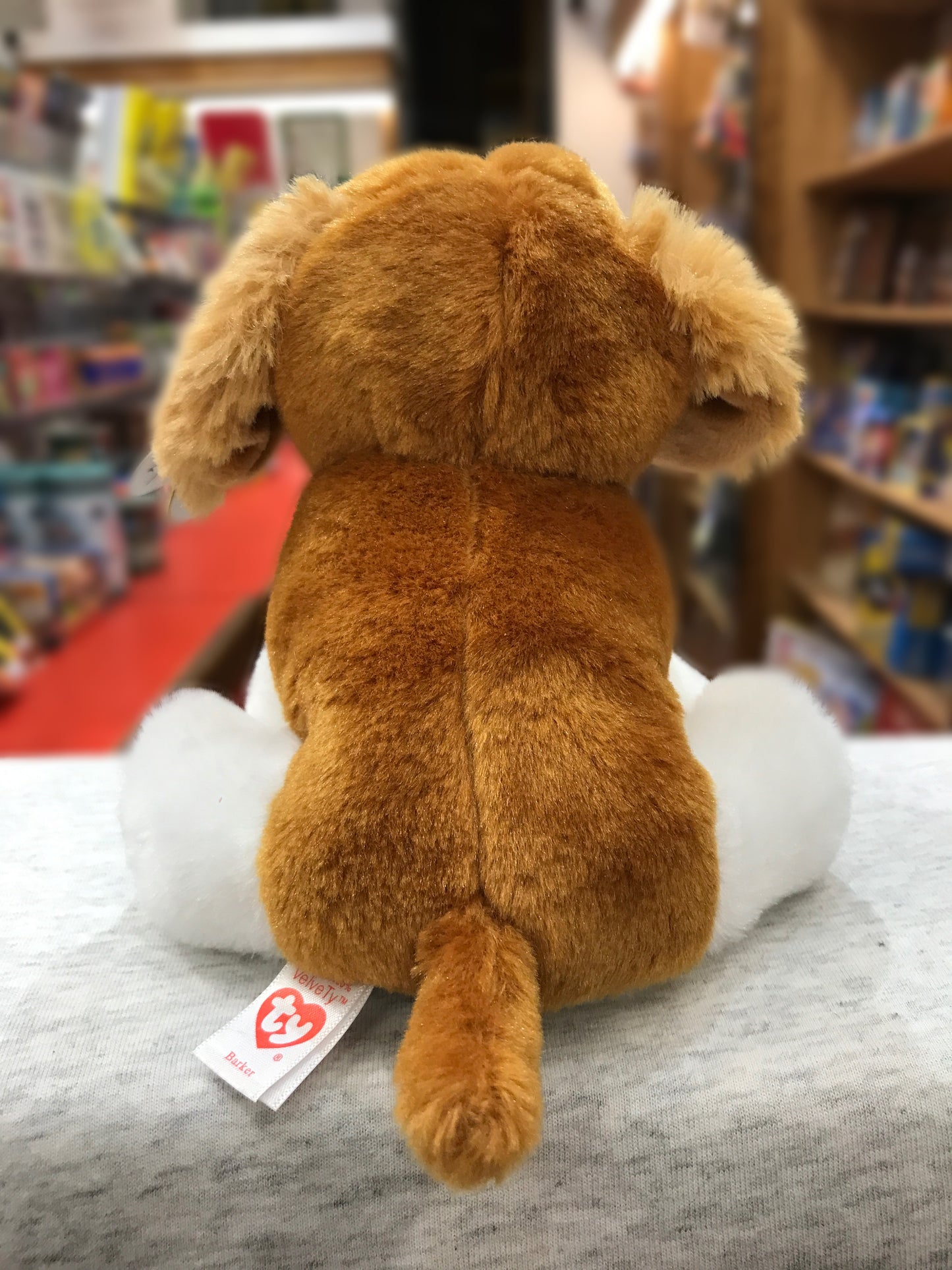 Ty Beanie Baby Barker, brown and white plush dog, sitting with back facing camera, Ty heart tag visible