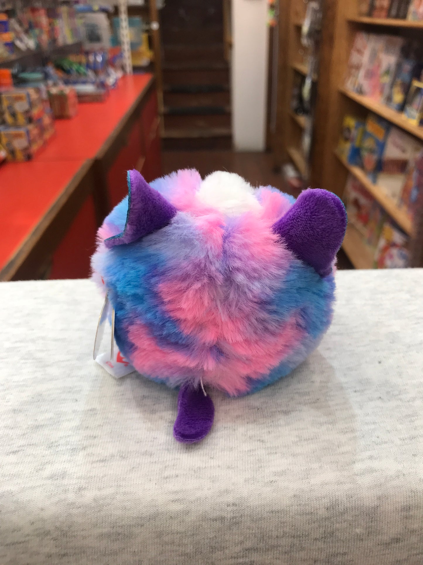 Colorful Ty Puffies Cleo husky plush toy with vibrant blue, pink, and purple fur, displayed in toy store setting