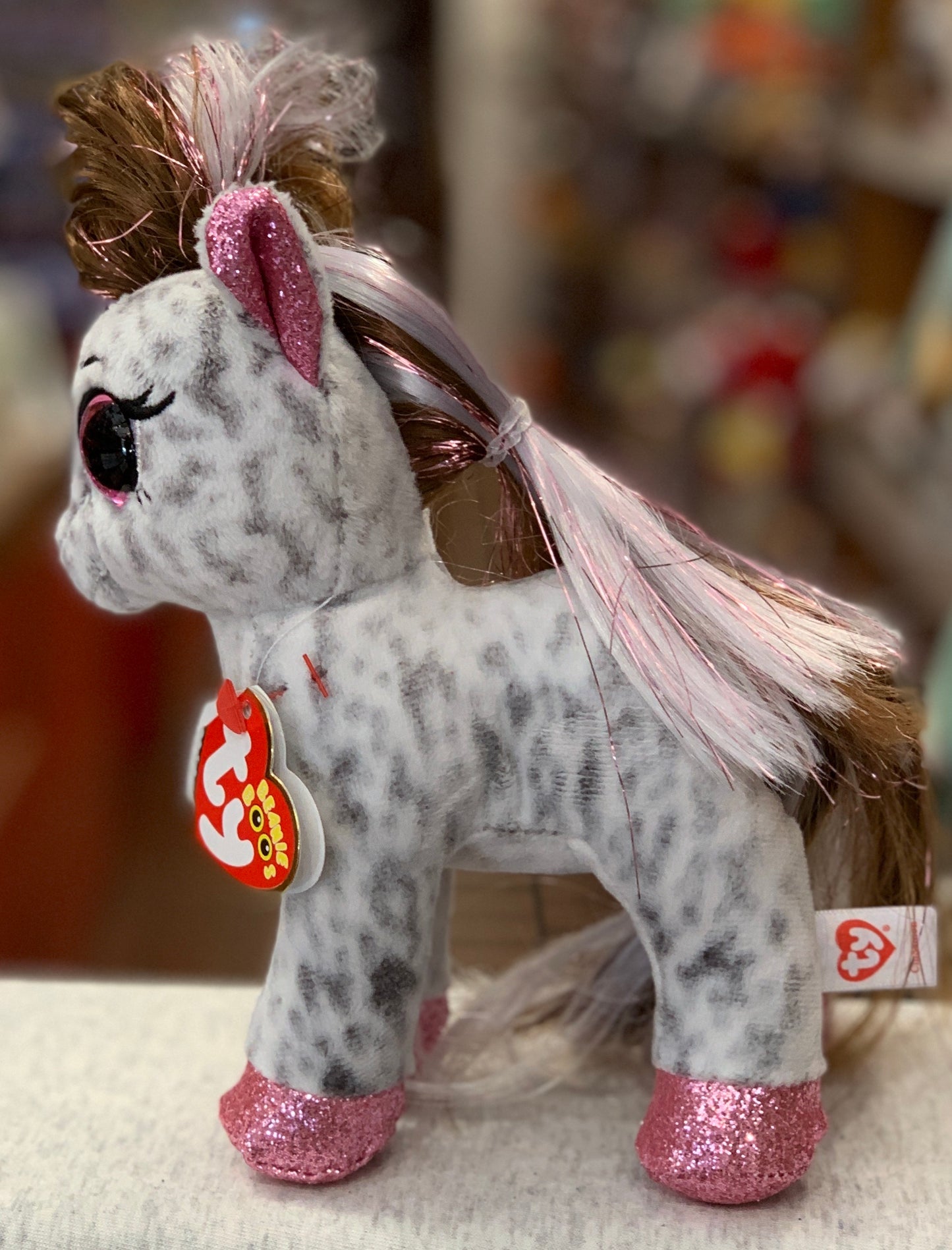 Ty Beanie Boo Cinnamon Pony plush toy with sparkly pink ears and hooves, colorful mane, and large eyes, shown with tag attached