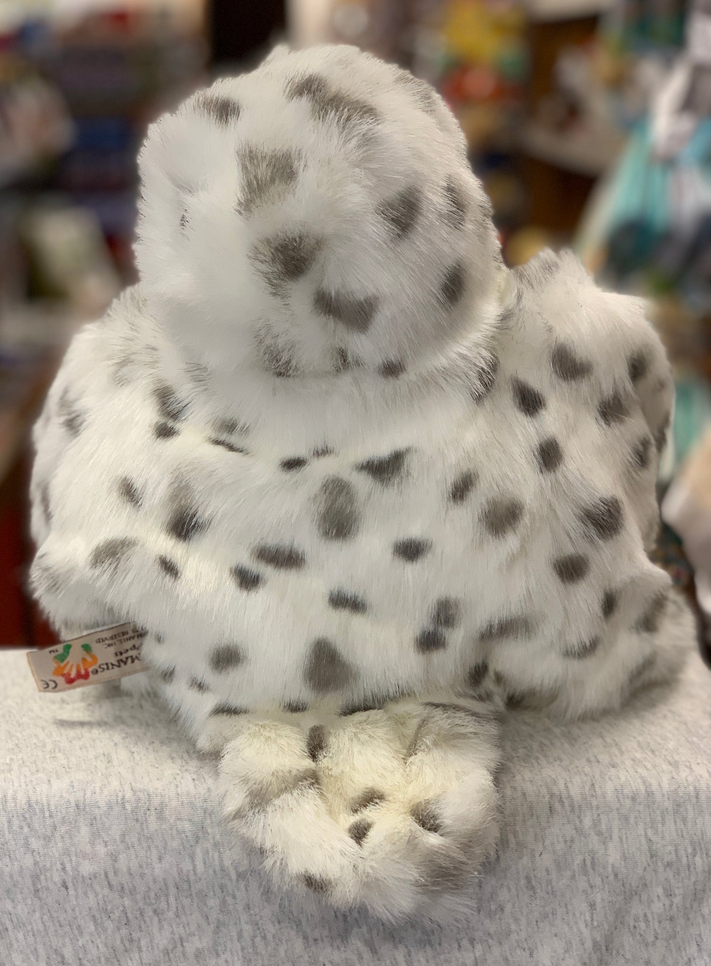 Folkmanis Snowy Owl hand puppet with soft white and gray spotted feathers, 21 inches tall, facing away to show realistic wing detail