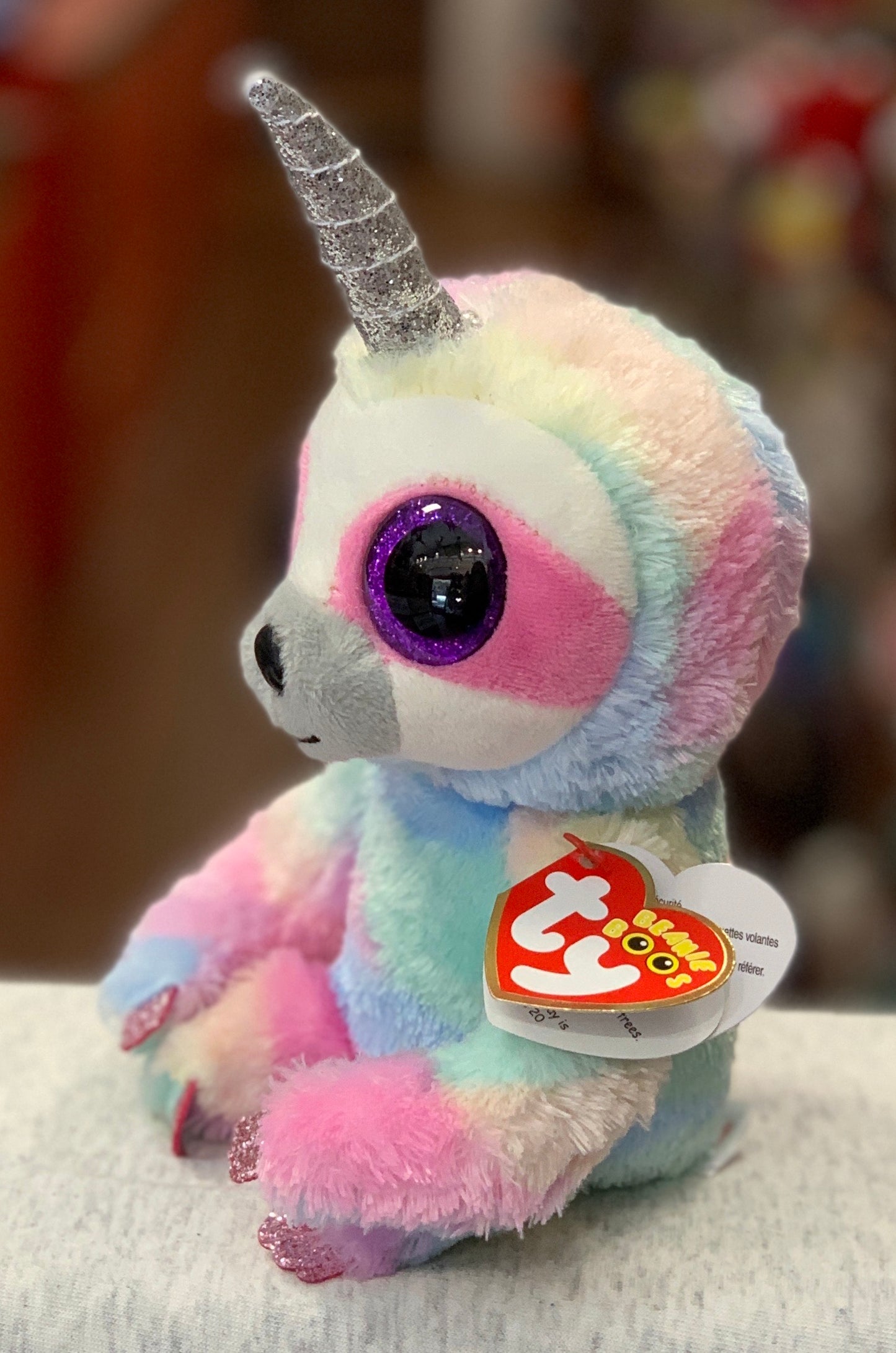 Pastel unicorn Ty Beanie Boo plush toy with glittery horn, large purple eyes, and heart-shaped tag, perfect for collectors