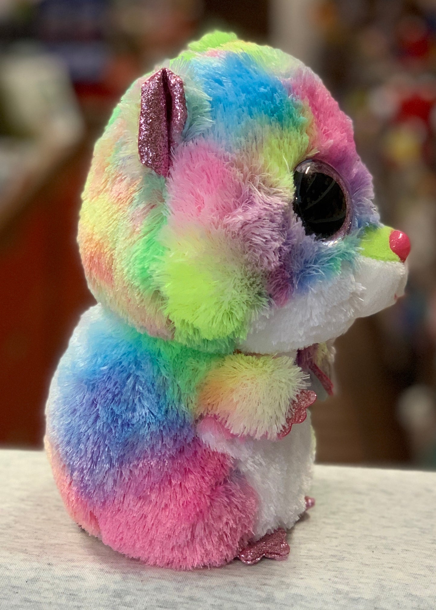 Colorful Ty Beanie Boo plush hamster Rodney with rainbow fur, large sparkly eyes, and glittery ears and paws