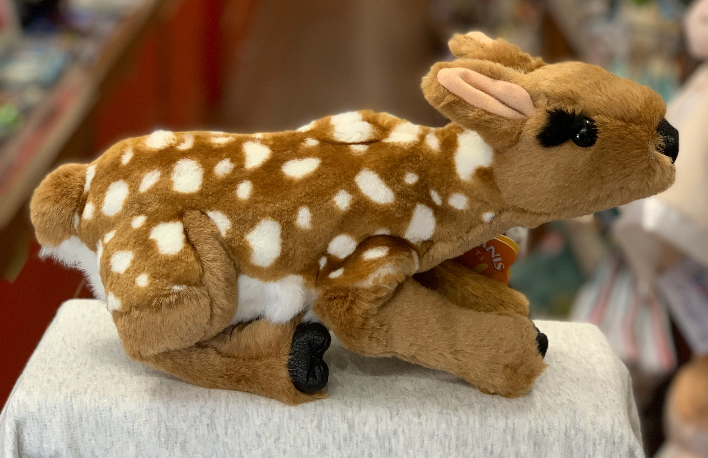 Folkmanis Fawn hand puppet with realistic spotted fur, big black eyes, and soft vinyl features, displayed on white surface