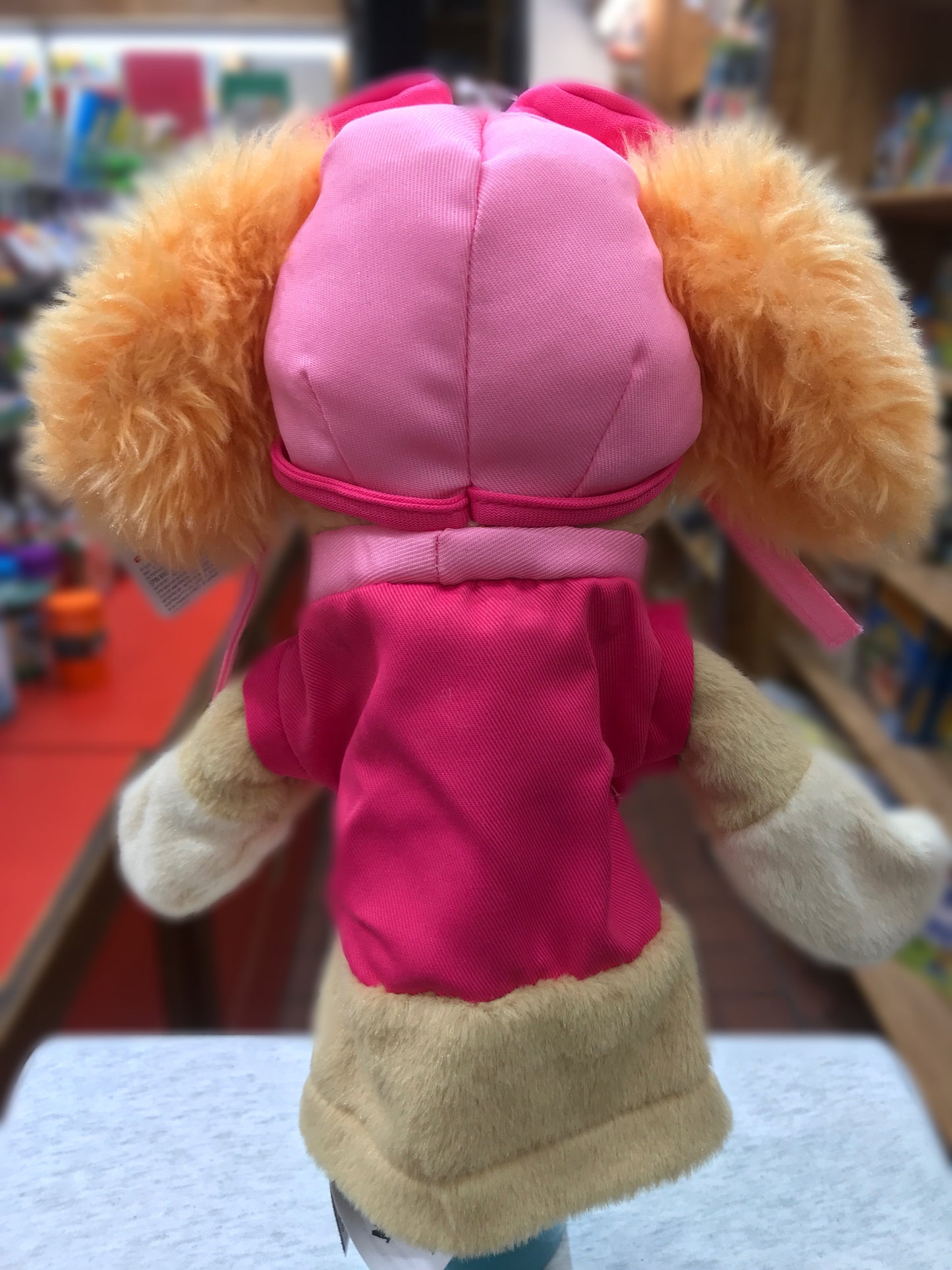 Gund Paw Patrol Skye hand puppet, pink and tan plush toy with floppy ears, viewed from behind on store shelf