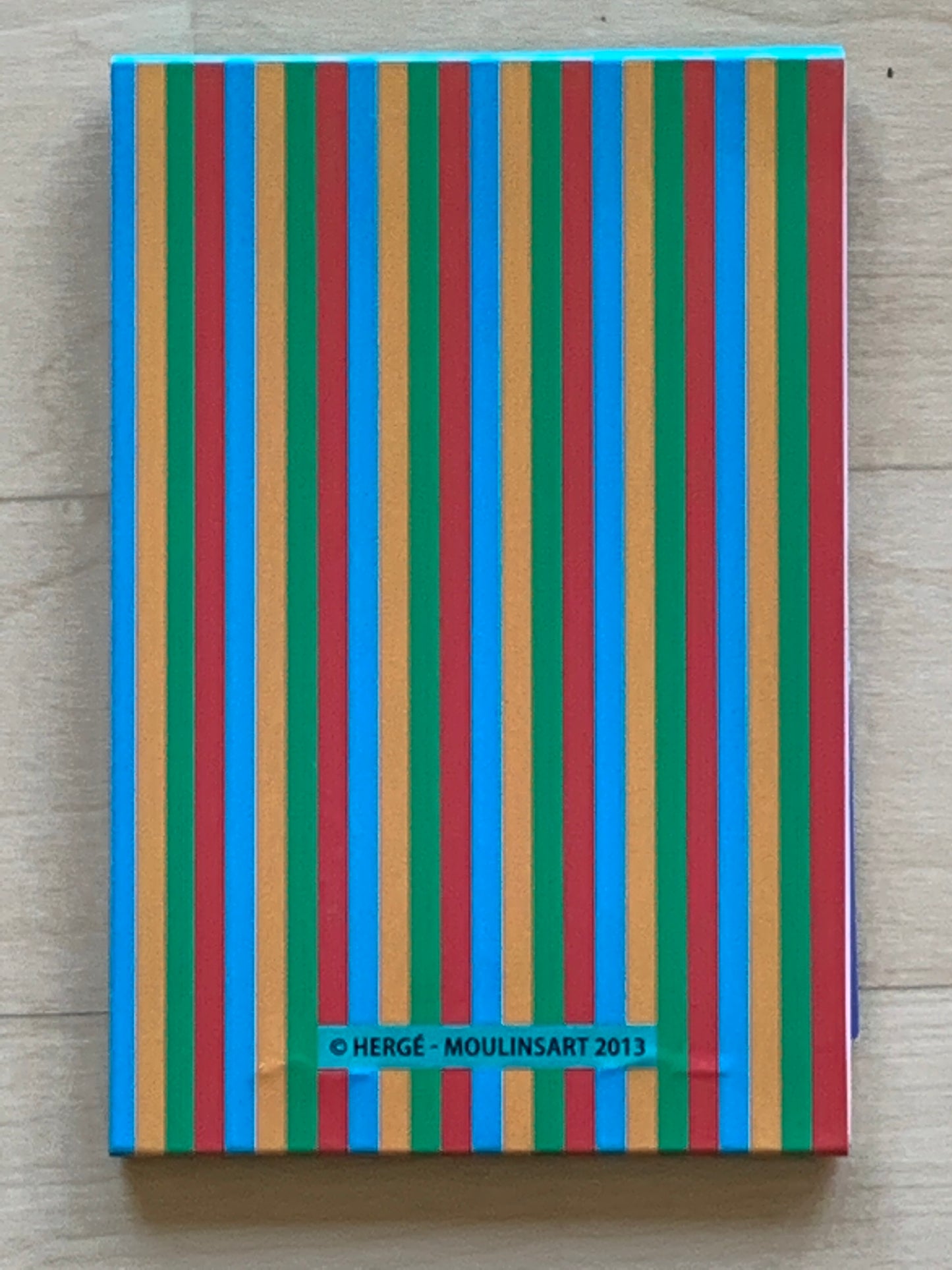 Colorful striped Tintin notepad cover with blue, green, red, and orange vertical lines, featuring Hergé-Moulinsart 2013 copyright