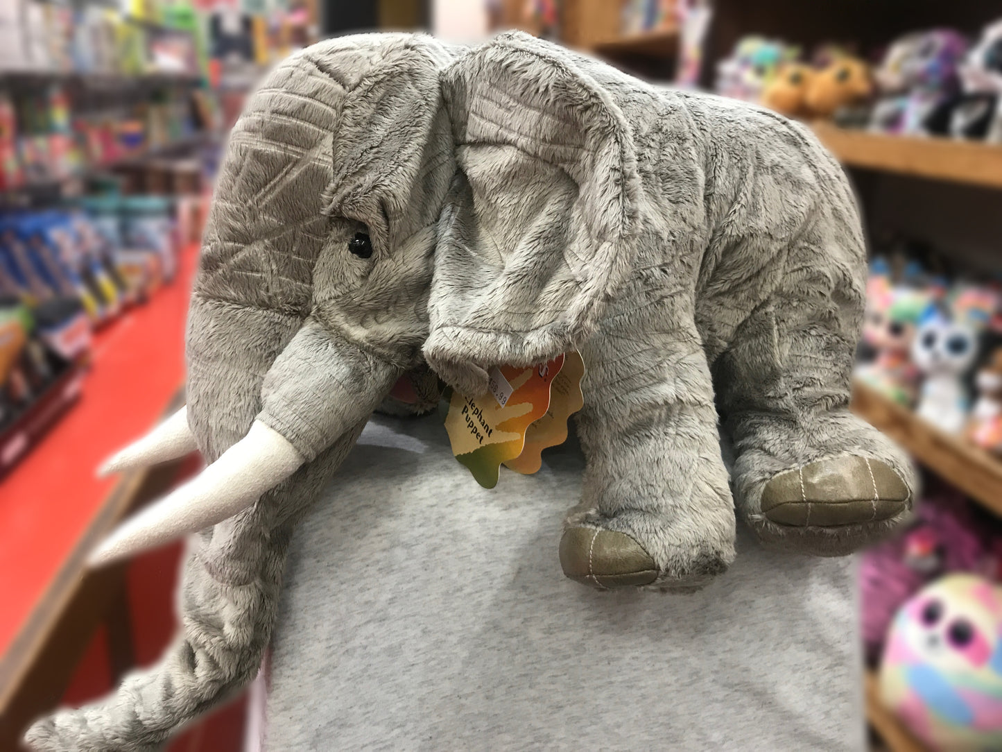 Folkmanis Elephant Puppet with movable trunk and realistic details, displayed in toy store setting
