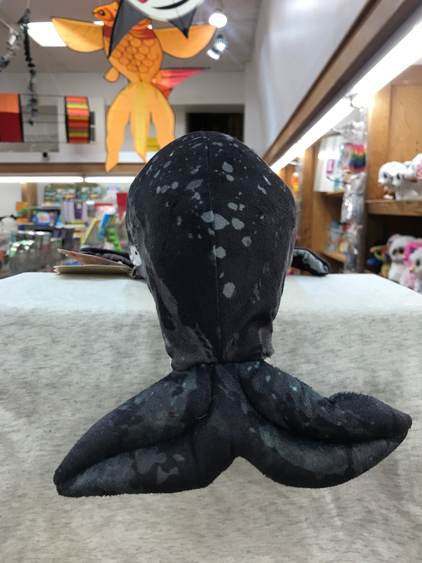 Realistic 28-inch Folkmanis narwhal puppet with mottled black skin and fluke, displayed in toy store setting