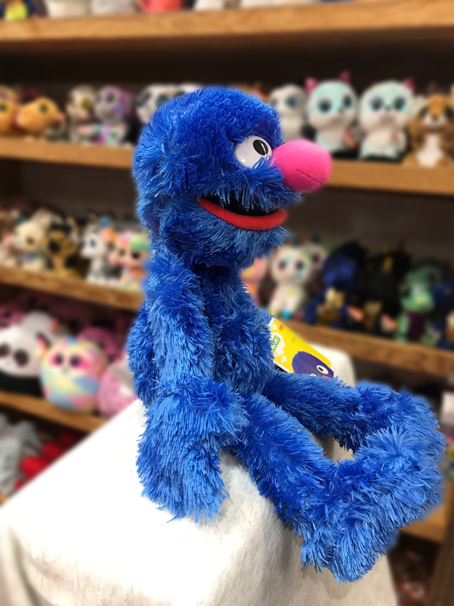Soft blue Gund Grover plush toy from Sesame Street sitting on display with other stuffed animals in background