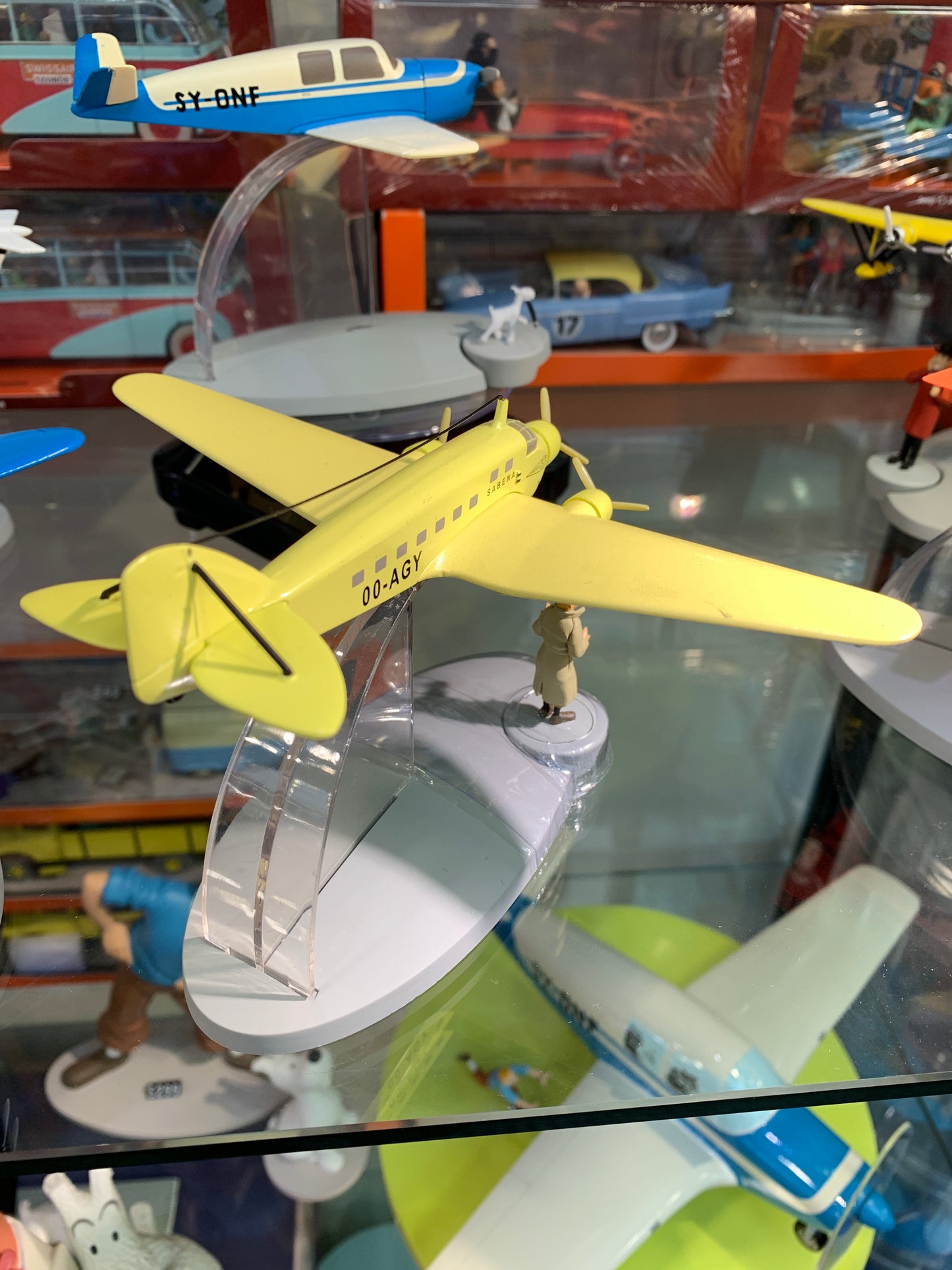 Yellow Sabena aircraft model from Tintin's The Black Island, displayed with other vintage toy planes and figurines