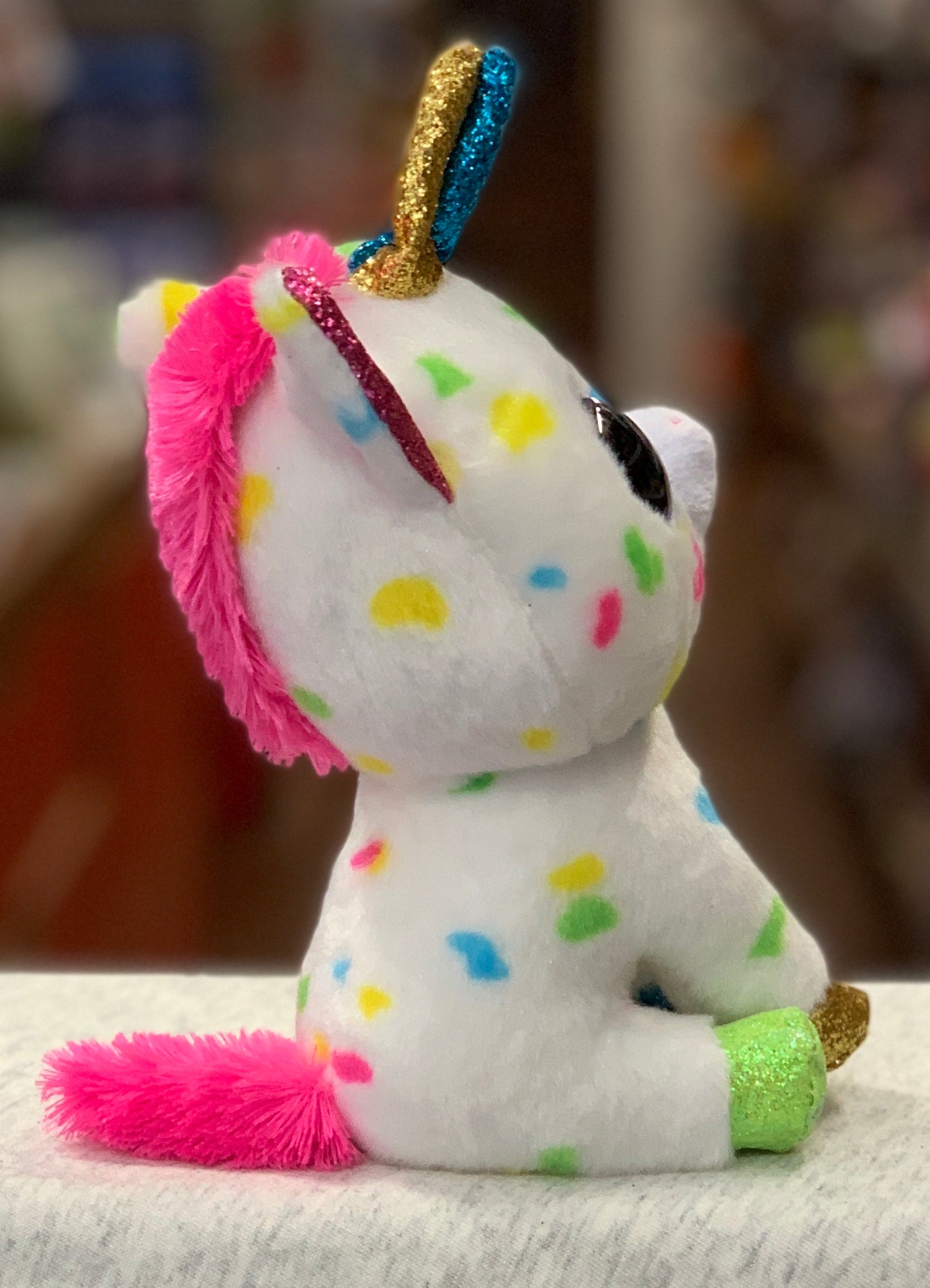 Colorful Ty Beanie Boo Harmonie unicorn plush toy with sparkly horn, pink mane, and multicolored spots on white body