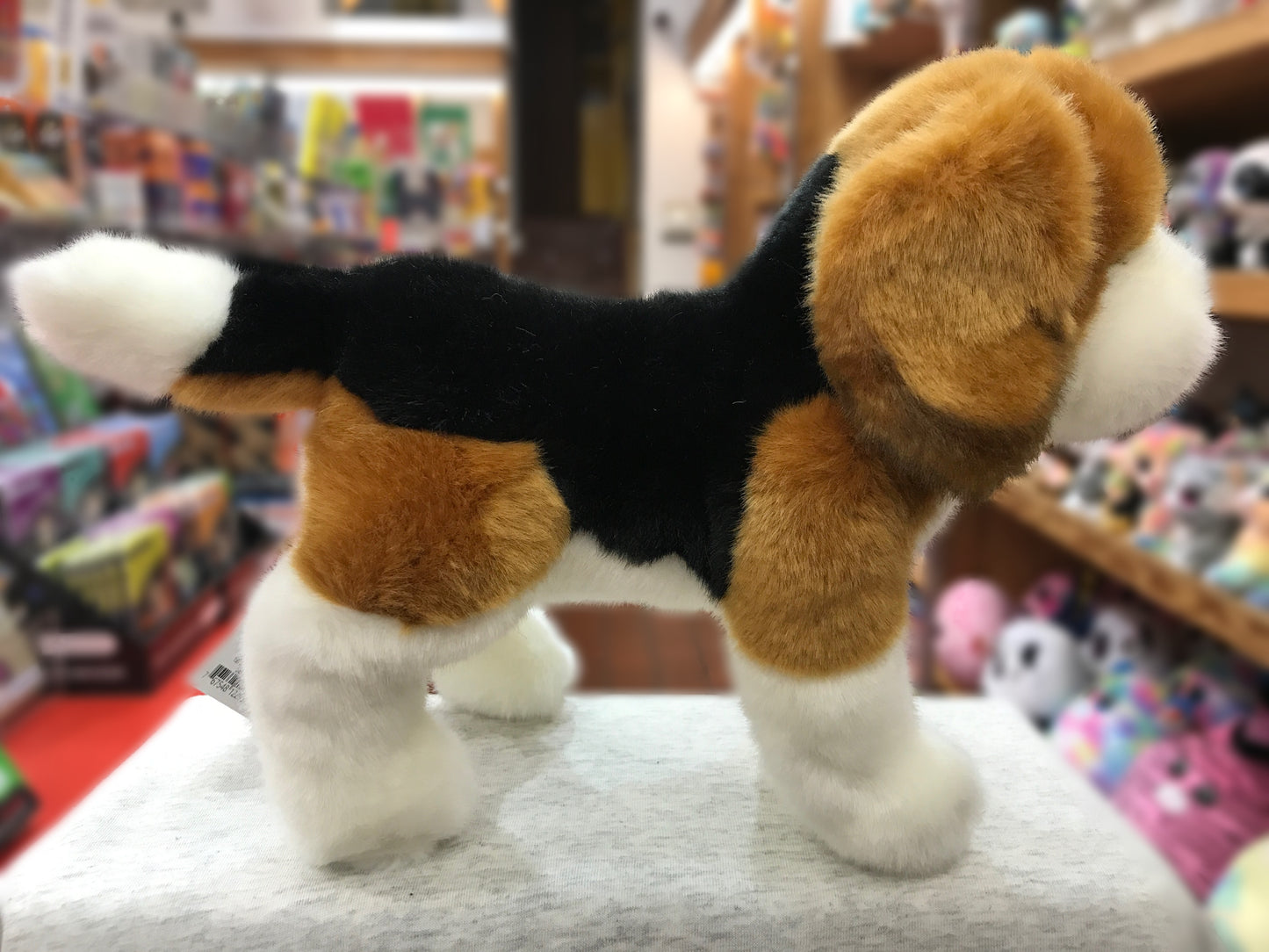 Lifelike Beagle plush toy with tri-color coat, floppy ears, and white-tipped tail displayed in toy store setting