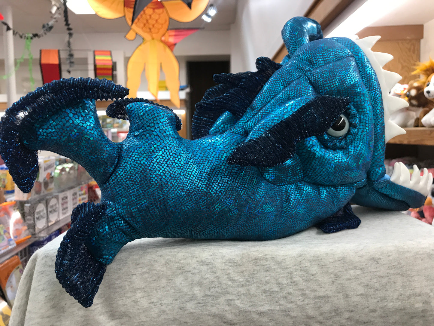 Folkmanis Anglerfish Puppet: Shimmering blue plush toy with movable mouth and eyes, displayed in a toy store setting
