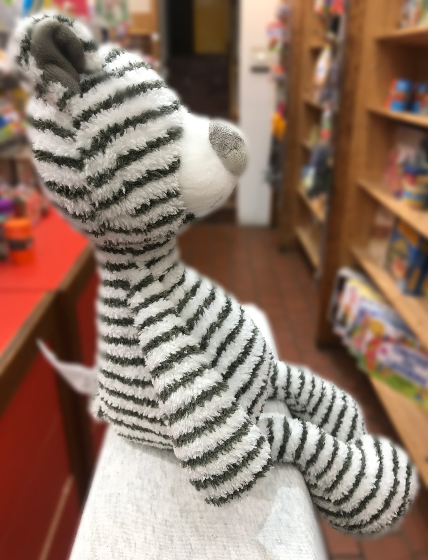Gund Zag Bear plush toy with grey and white horizontal stripes, large snout, in toy store setting