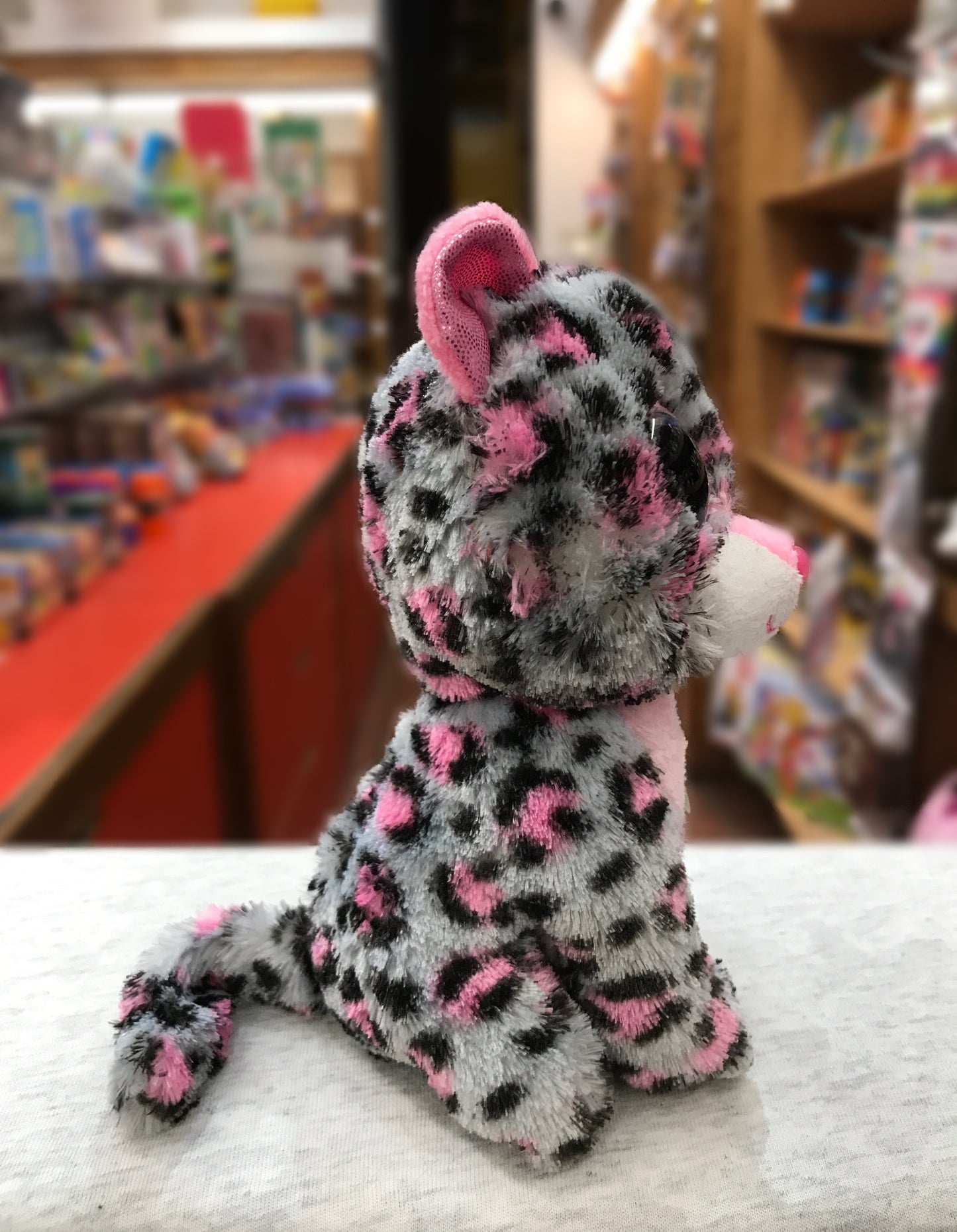 Ty Beanie Boo Tasha Kitty plush toy with pink and gray leopard print fur, sitting on display in a toy store