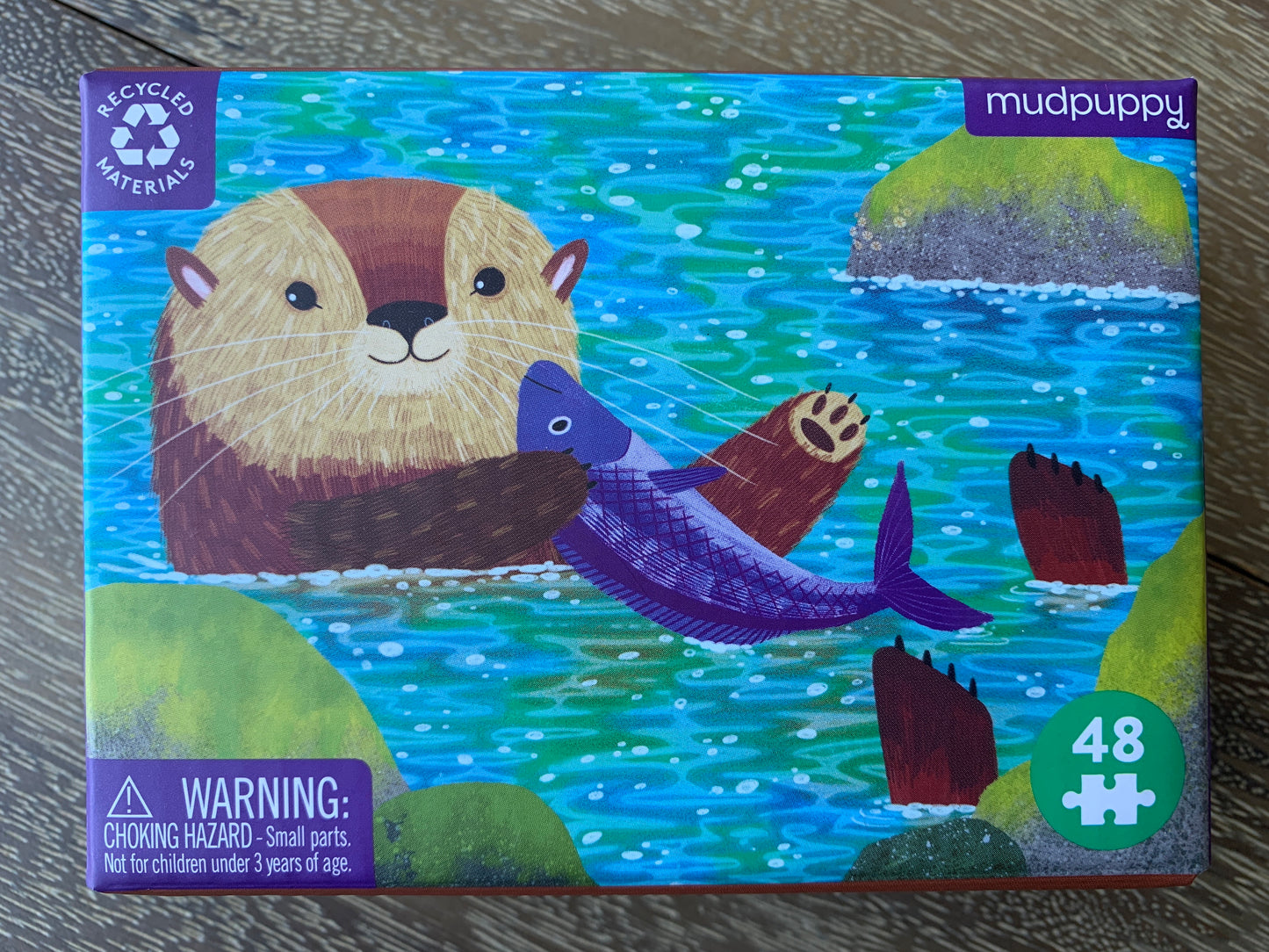 Mudpuppy Otter Gift Box: 48-piece puzzle featuring cute otter holding purple fish in water, eco-friendly packaging