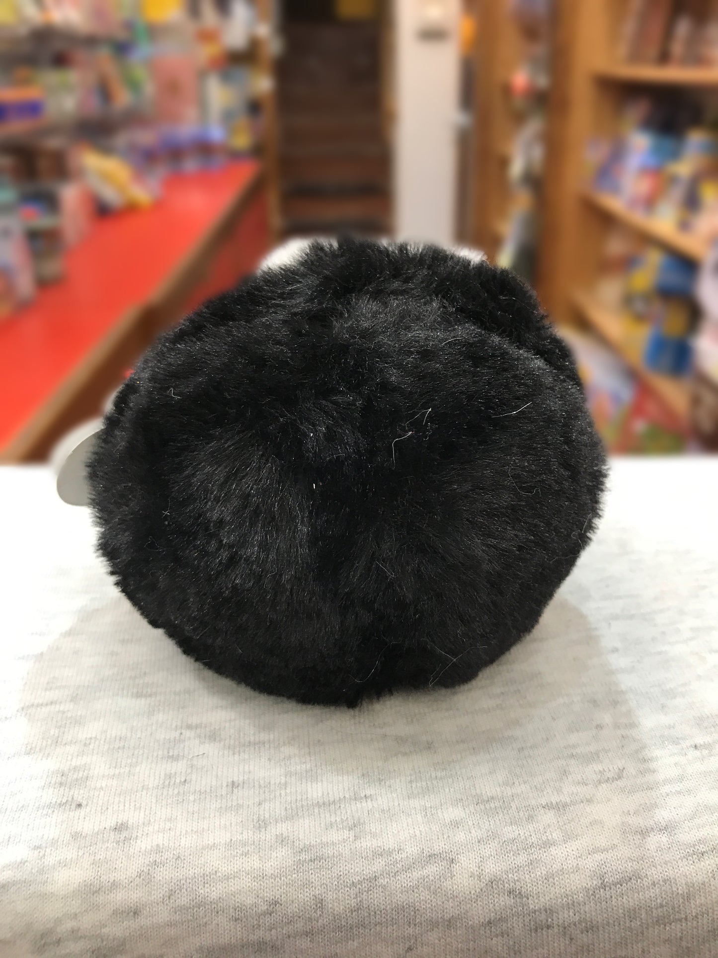 Round, black Ty Puffies Waddles penguin plush toy sitting upright on display in toy store, 4 inches tall