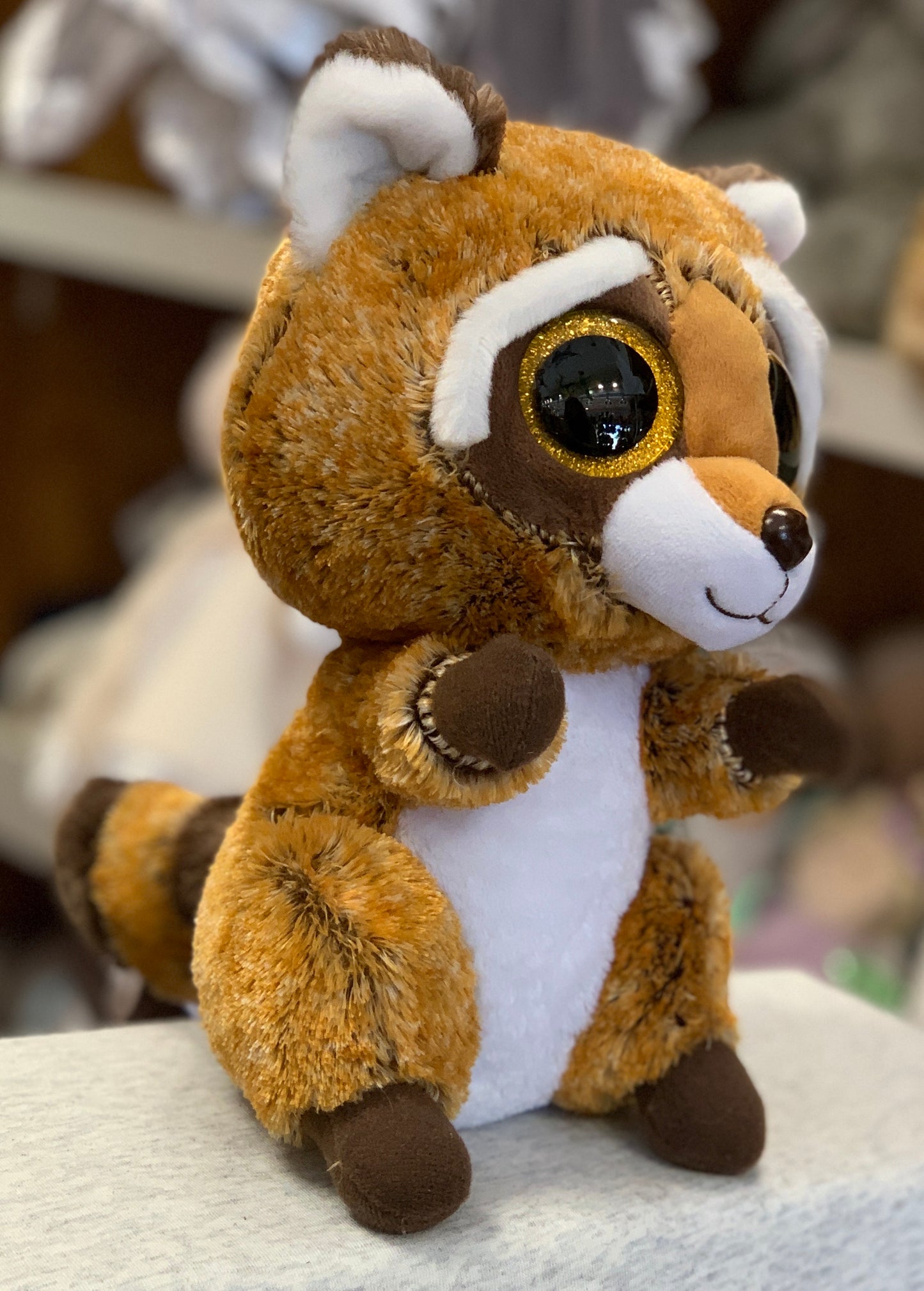 Adorable Ty Beanie Boo Rusty Raccoon plush toy with large glittery eyes, soft orange fur, and white belly, perfect for cuddling