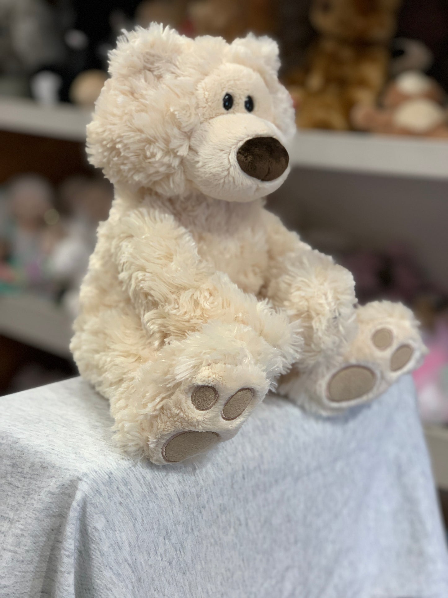 Gund Philbin beige teddy bear plush with big paws and curious expression, sitting on display for cuddly bear hugs