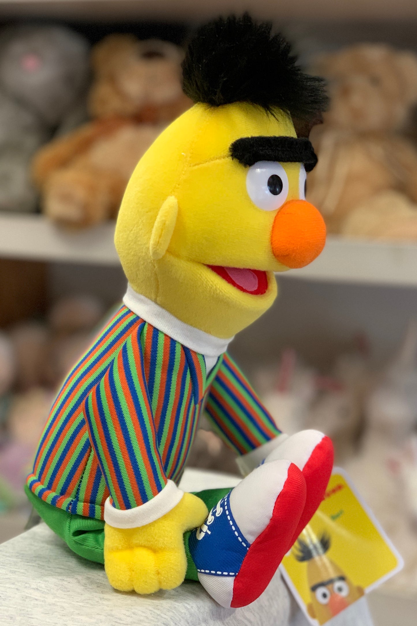 Gund Sesame Street Bert plush toy, 14 inches tall, with yellow face, black hair, orange nose, and colorful striped shirt
