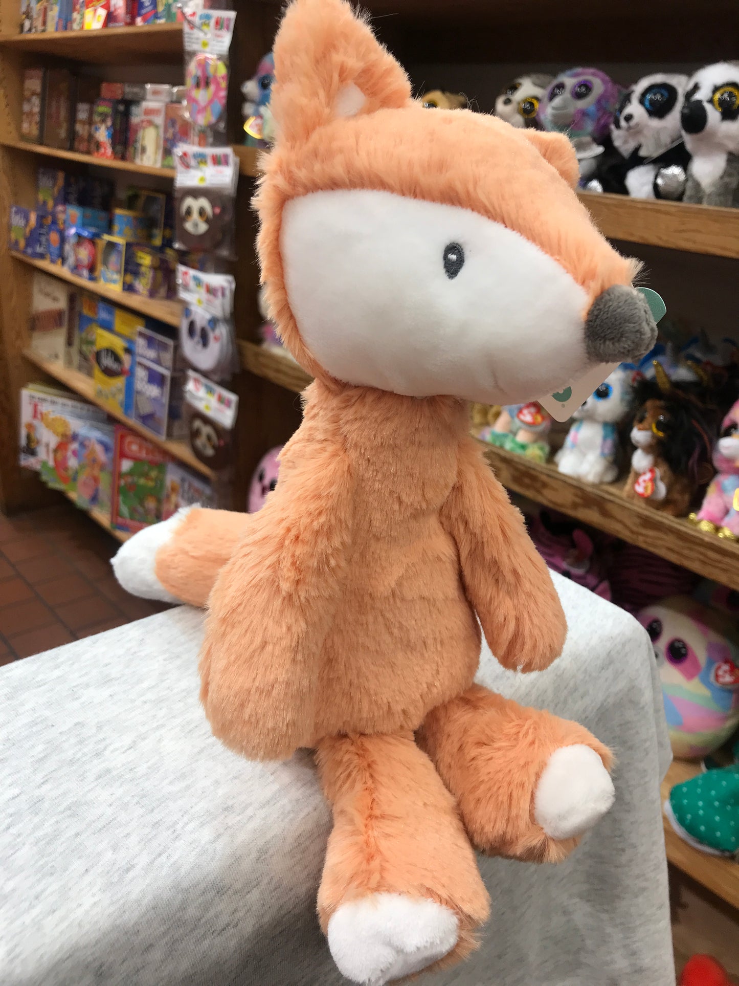 Soft plush Gund Baby Toothpick Fox toy, light orange with white accents, sitting in toy store display