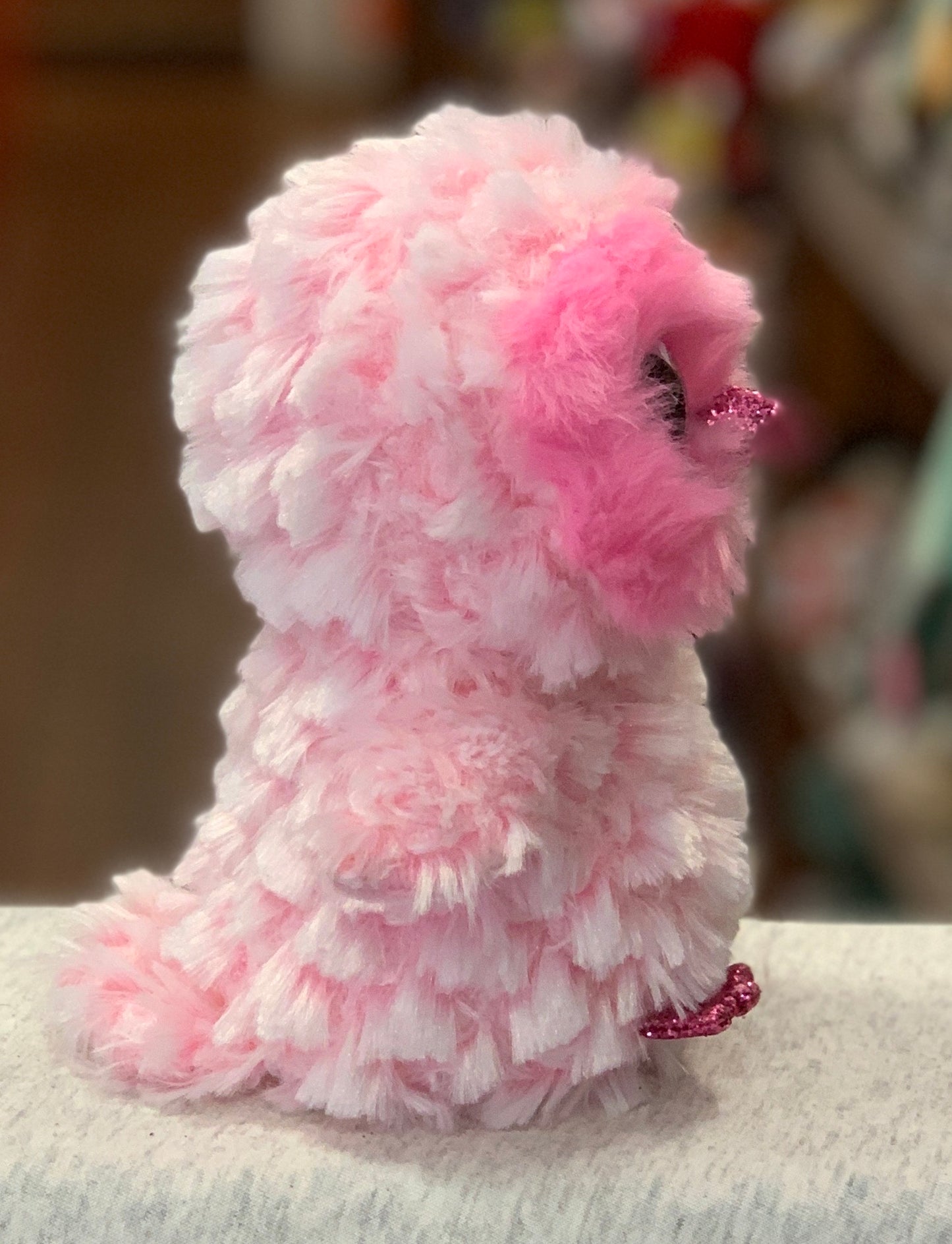 Fluffy pink Ty Beanie Boo Twiggy Owl plush toy with glittery eyes and feet, sitting on a light surface