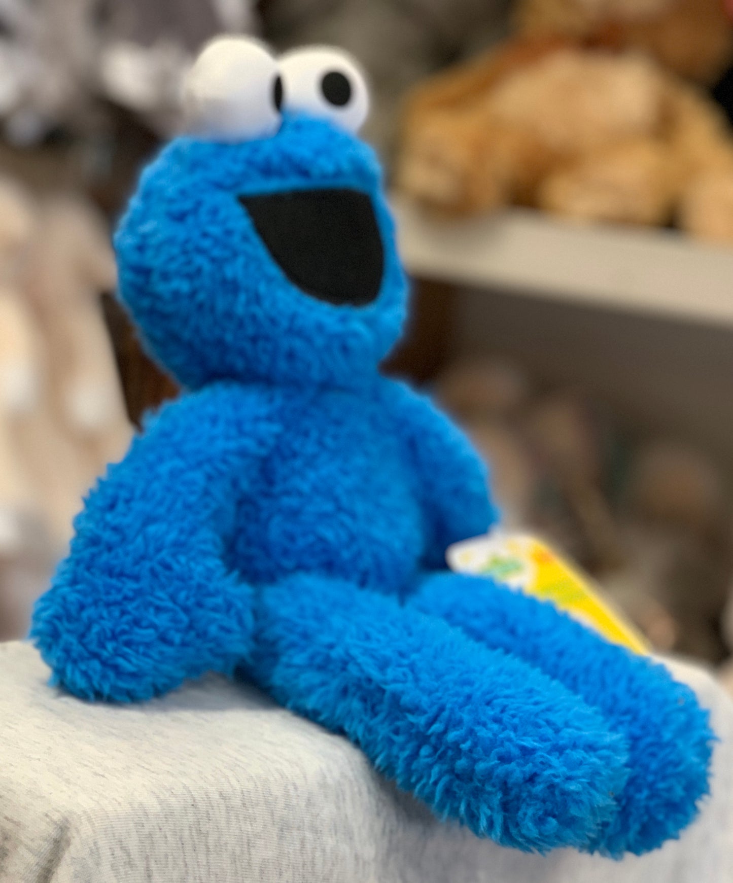 Gund Sesame Street Cookie Monster plush toy with long limbs, sitting on a surface, showcasing soft blue fur and characteristic eyes