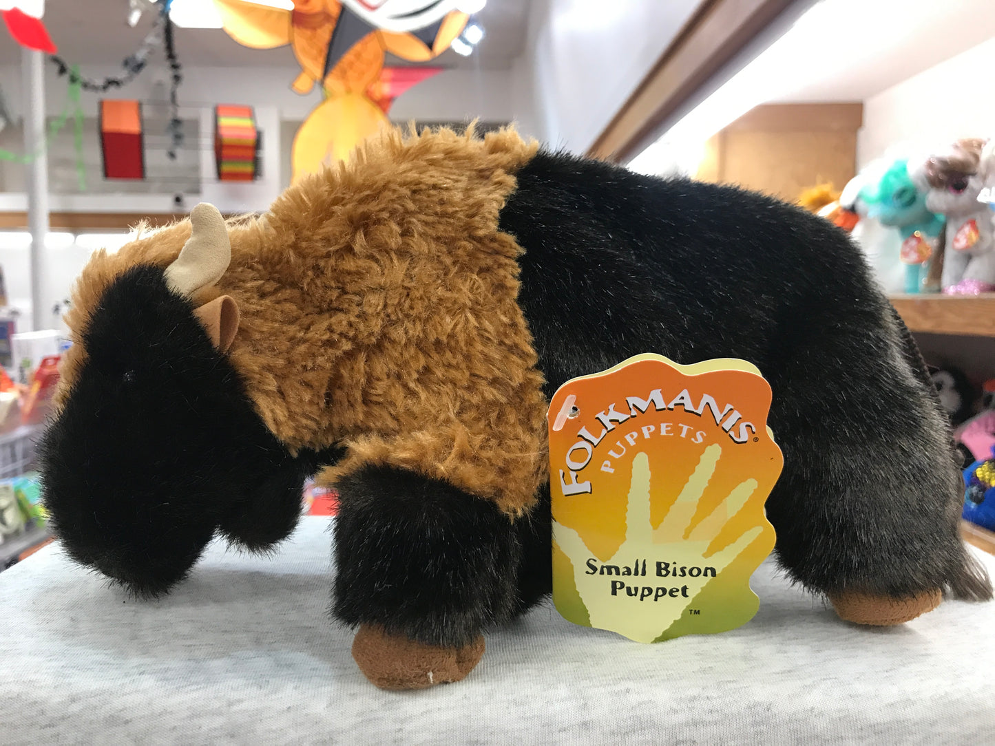 Folkmanis Small Bison Puppet, 10 inches long, with movable mouth and forelegs, displayed in toy store with product tag visible
