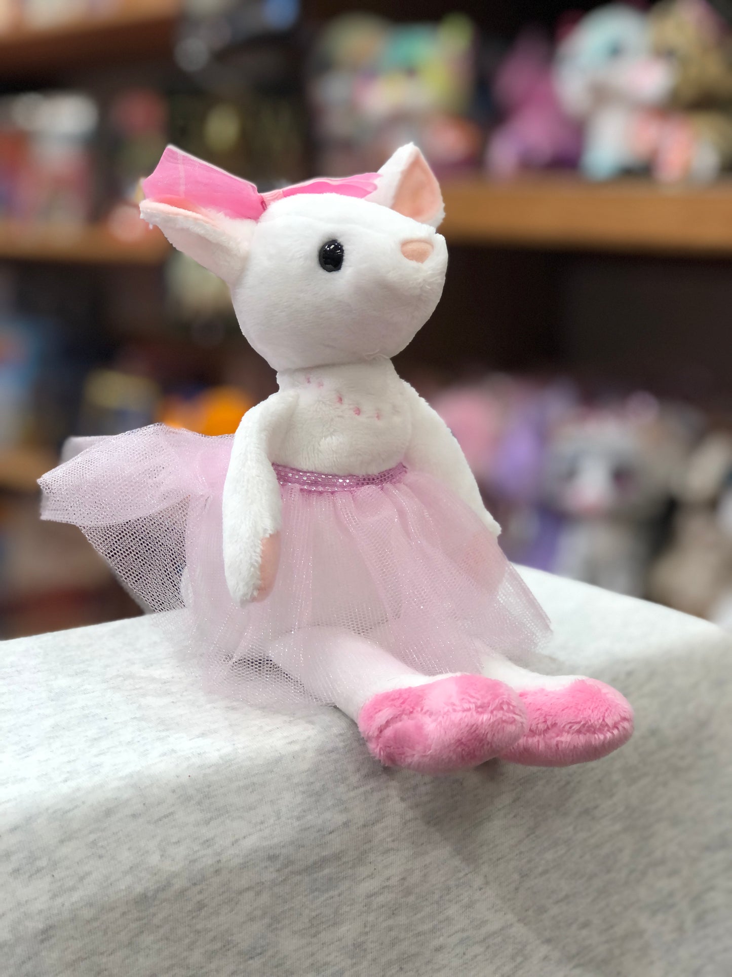 Adorable white ballerina mouse plush toy with pink tutu, bow, and ballet slippers, sitting on display in a toy store