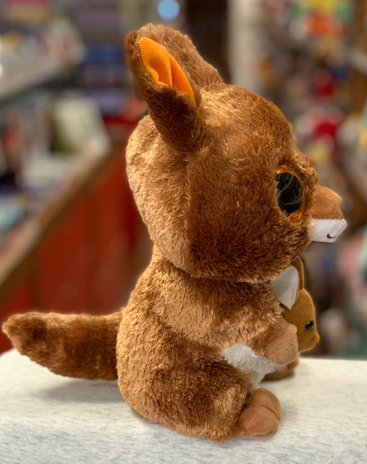 Ty Beanie Boo Kipper Kangaroo plush toy with brown fur, orange ears, and large sparkly eyes, sitting on display in a store