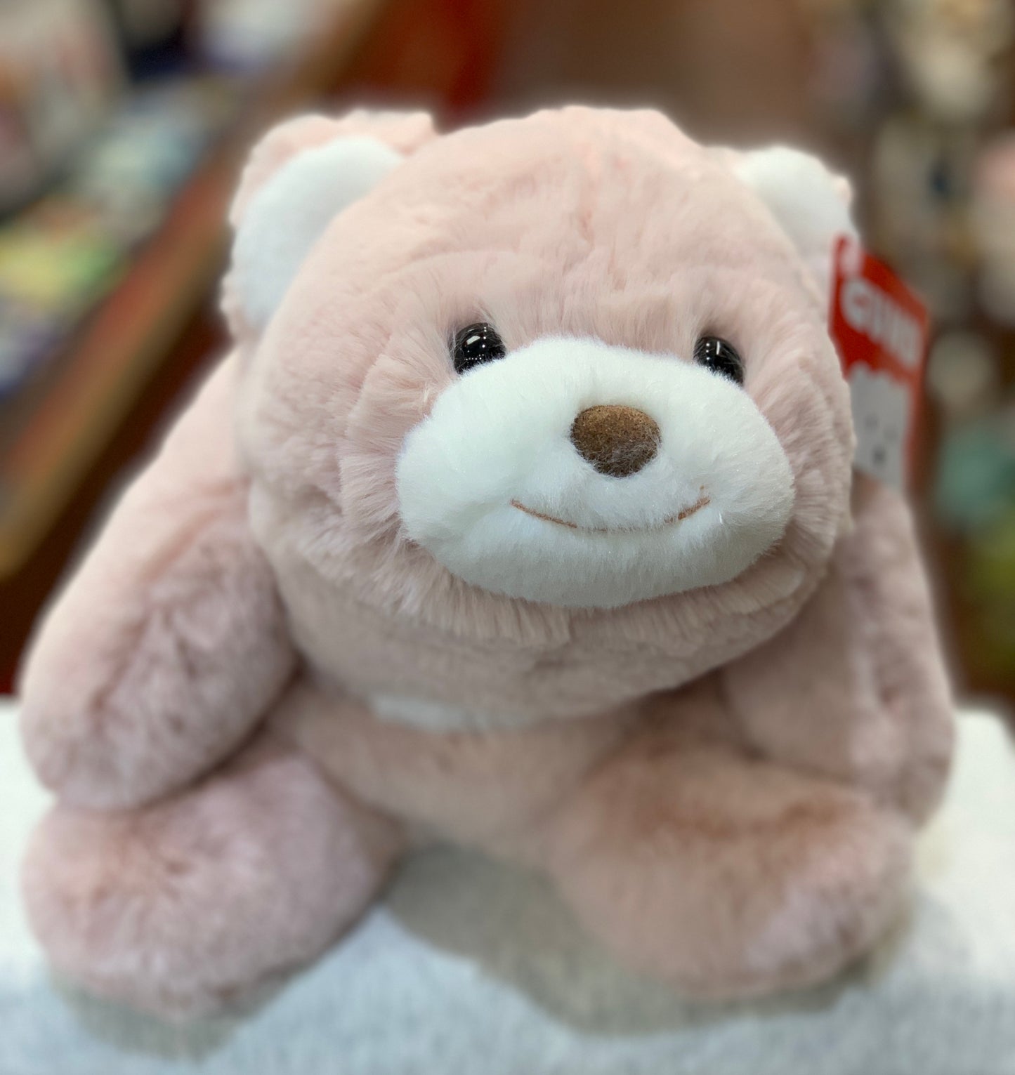 Gund Snuffles teddy bear in soft pink plush with white muzzle, smiling face, and crescent moon shape for hugging
