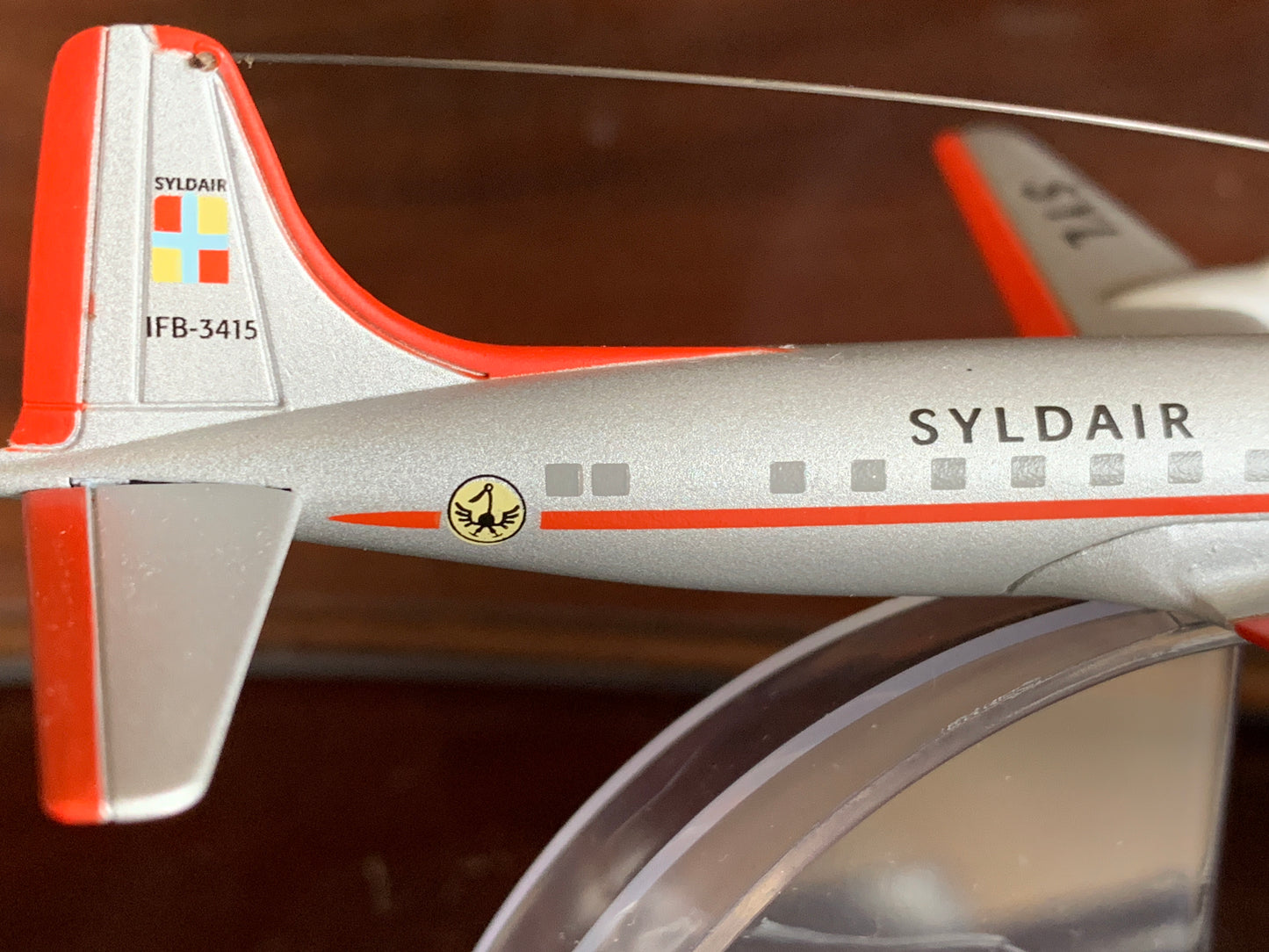 Syldair Douglas DC-6 model airplane from Tintin's Destination Moon, silver fuselage with red trim and logo, displayed on stand