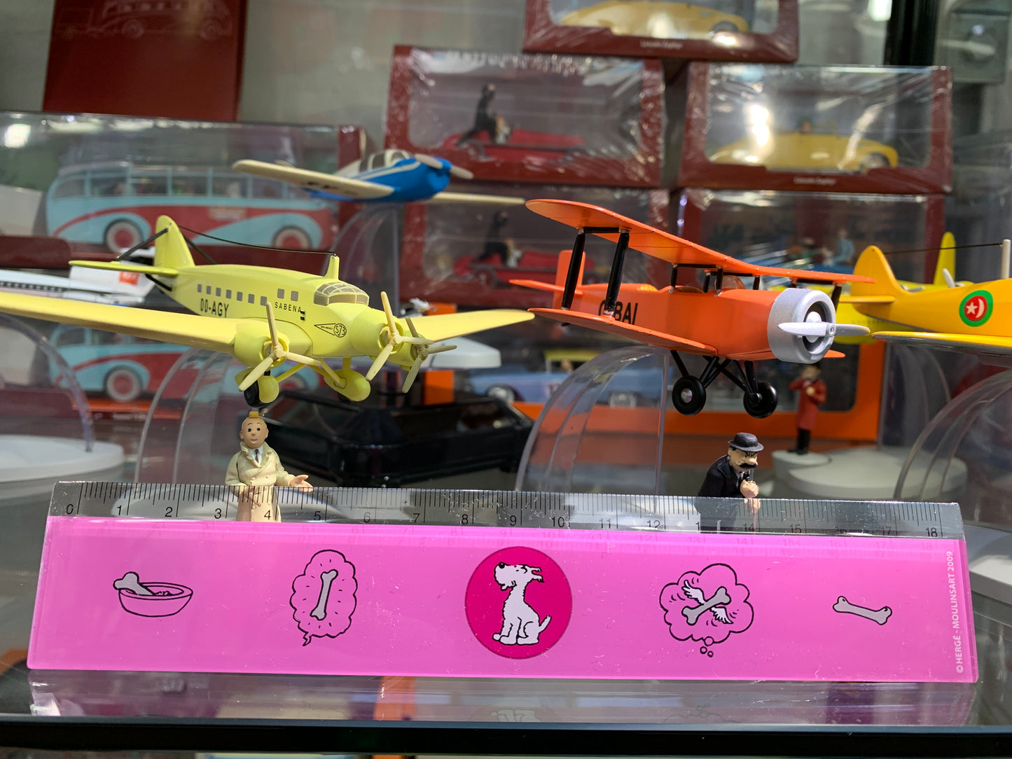 Tintin-themed 18cm ruler with Snowy illustrations, displayed with vintage toy planes and figurines in a collectibles showcase