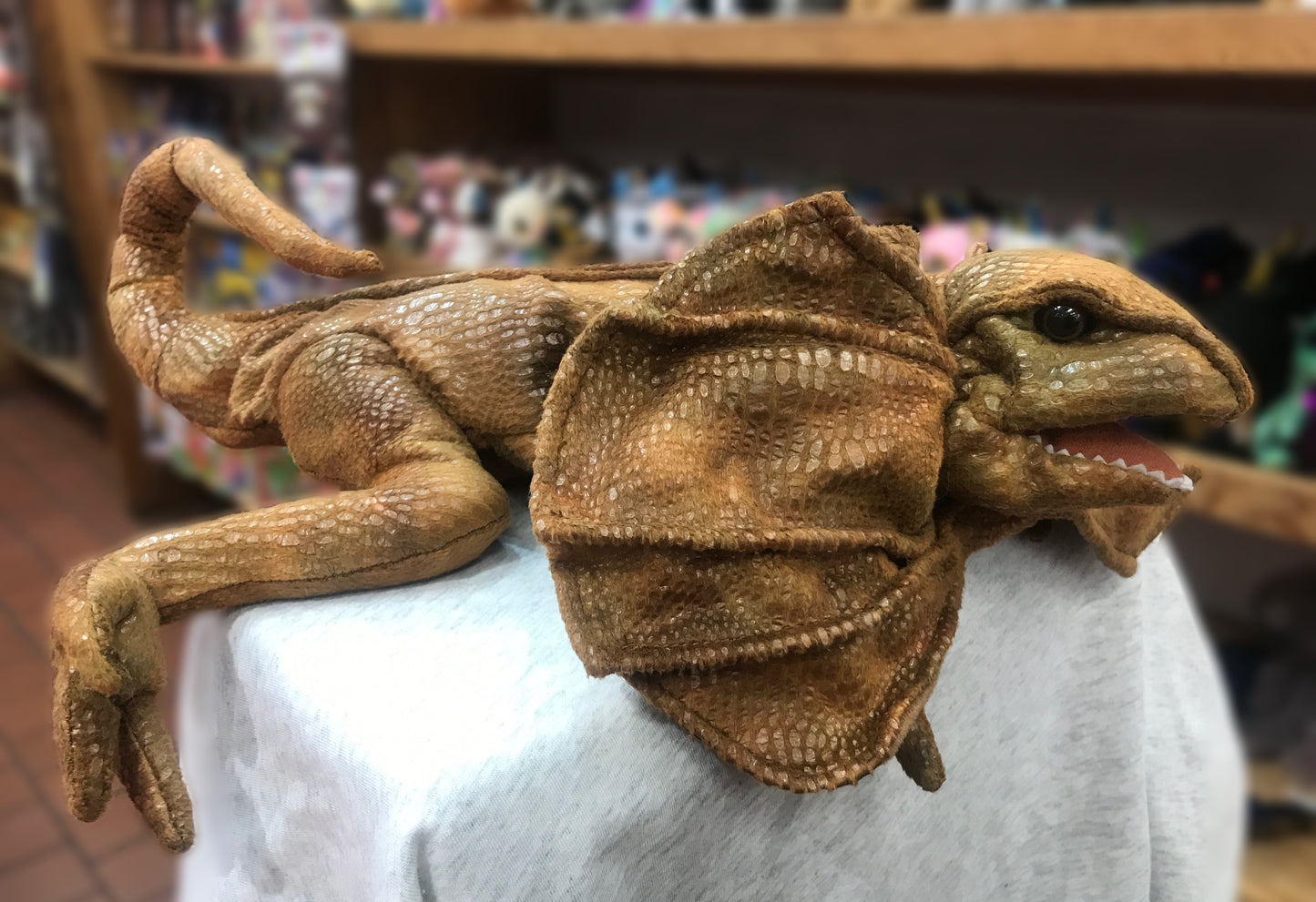 Folkmanis Frilled Lizard puppet with movable mouth and legs, showcasing realistic texture and playful pose on display