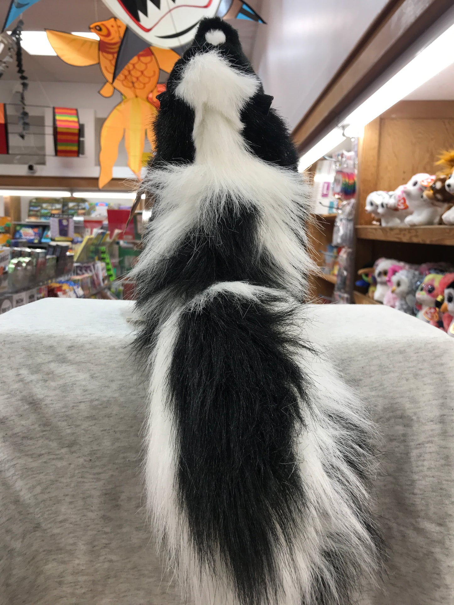 Folkmanis skunk puppet with black and white fur displayed in toy store, showcasing realistic details and movable parts