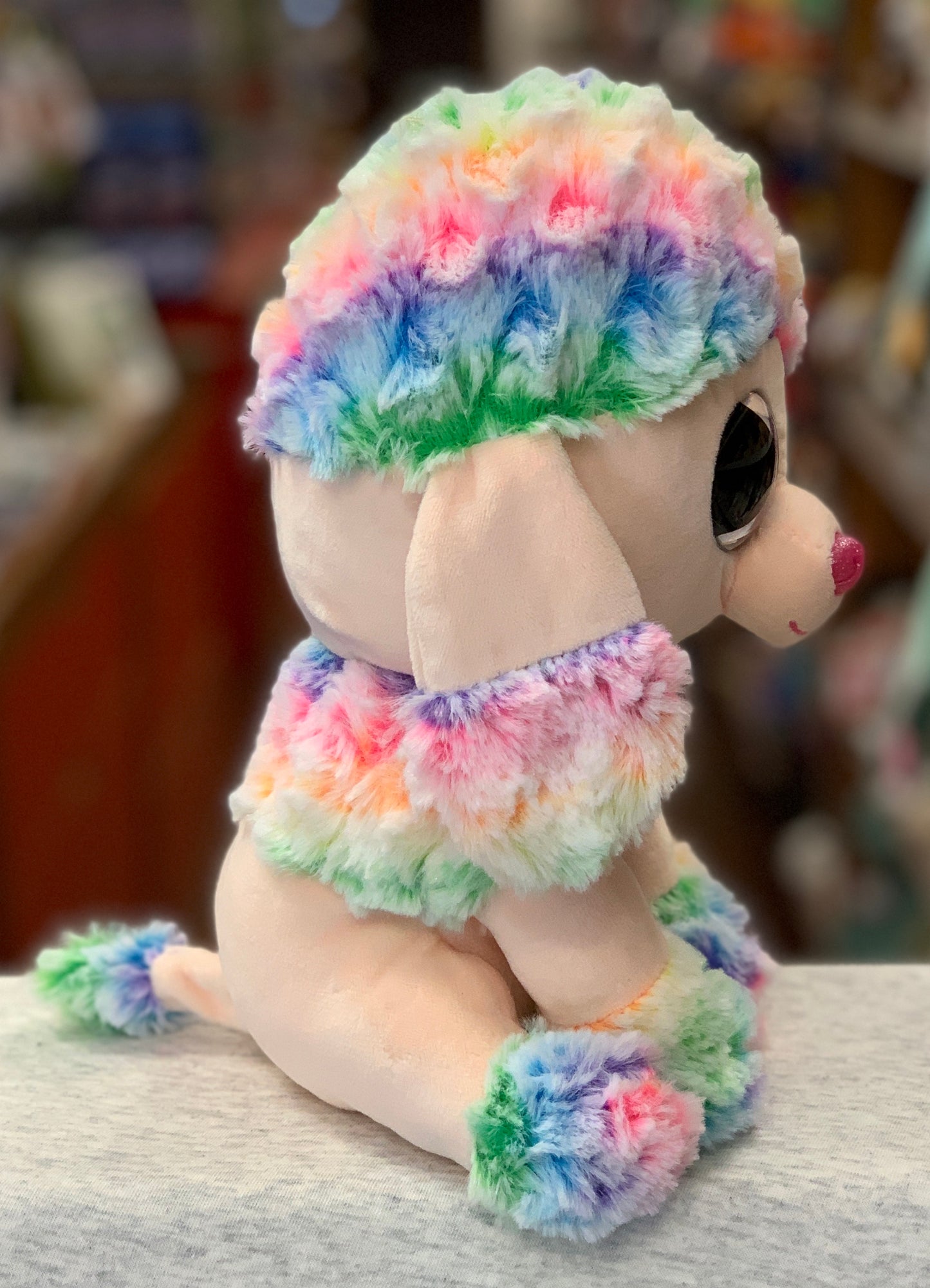 Ty Beanie Boo Rainbow Dog plush toy with colorful fur on head, collar, and paws, sitting on display