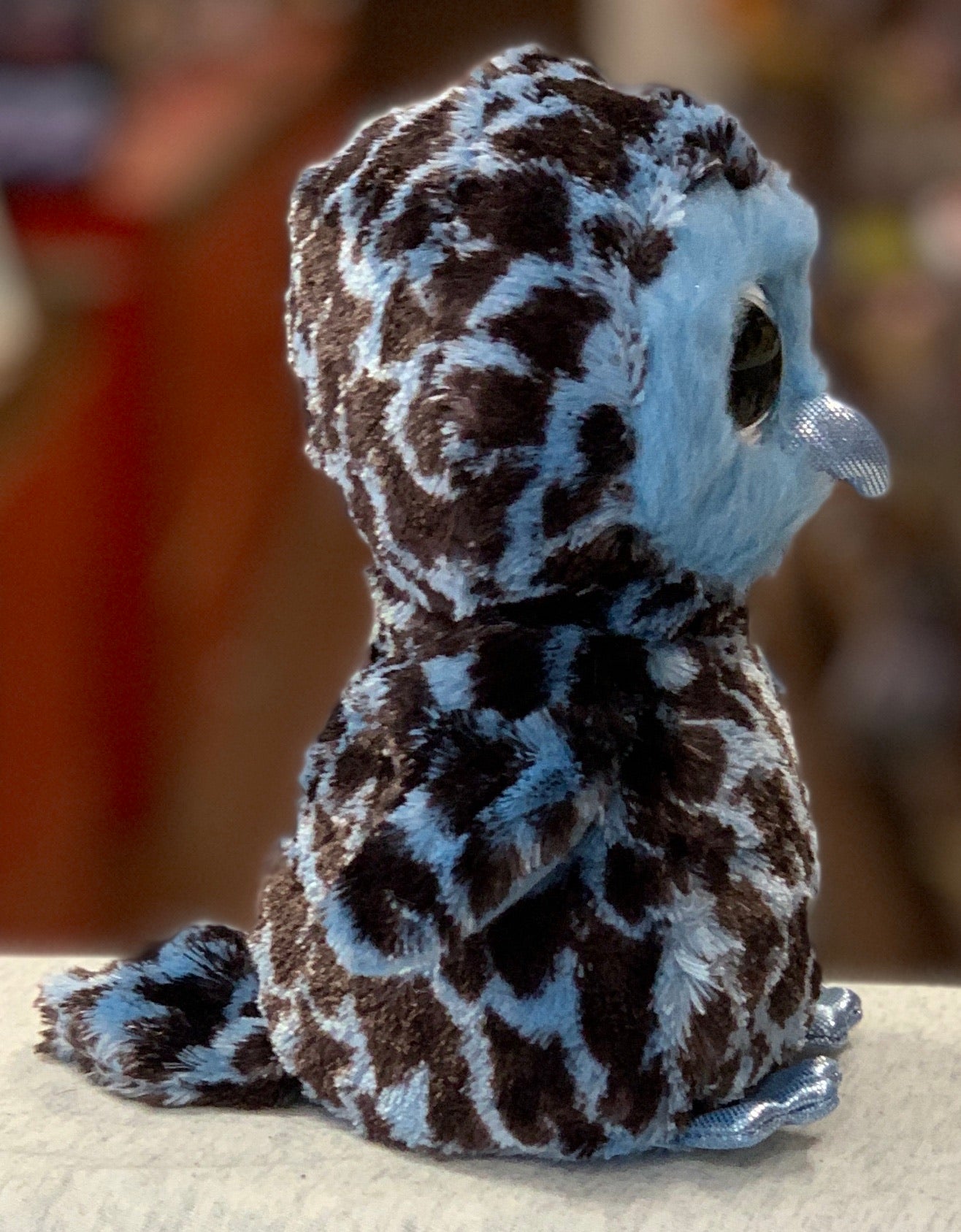 Ty Beanie Boo Yago owl plush toy with blue and brown patterned fur, sitting on a surface, side view of soft stuffed animal