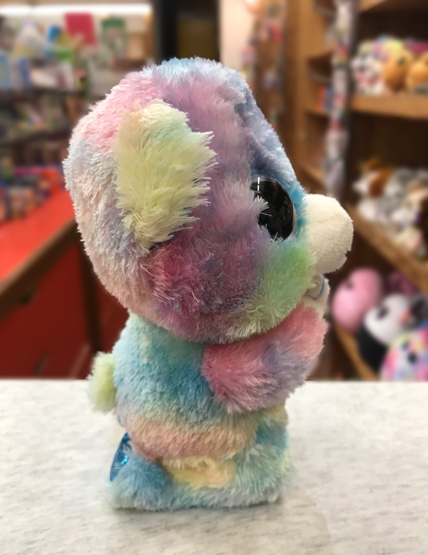 Colorful Ty Beanie Boo Hope praying bear plush toy on display, showcasing soft multicolored fur and large eyes