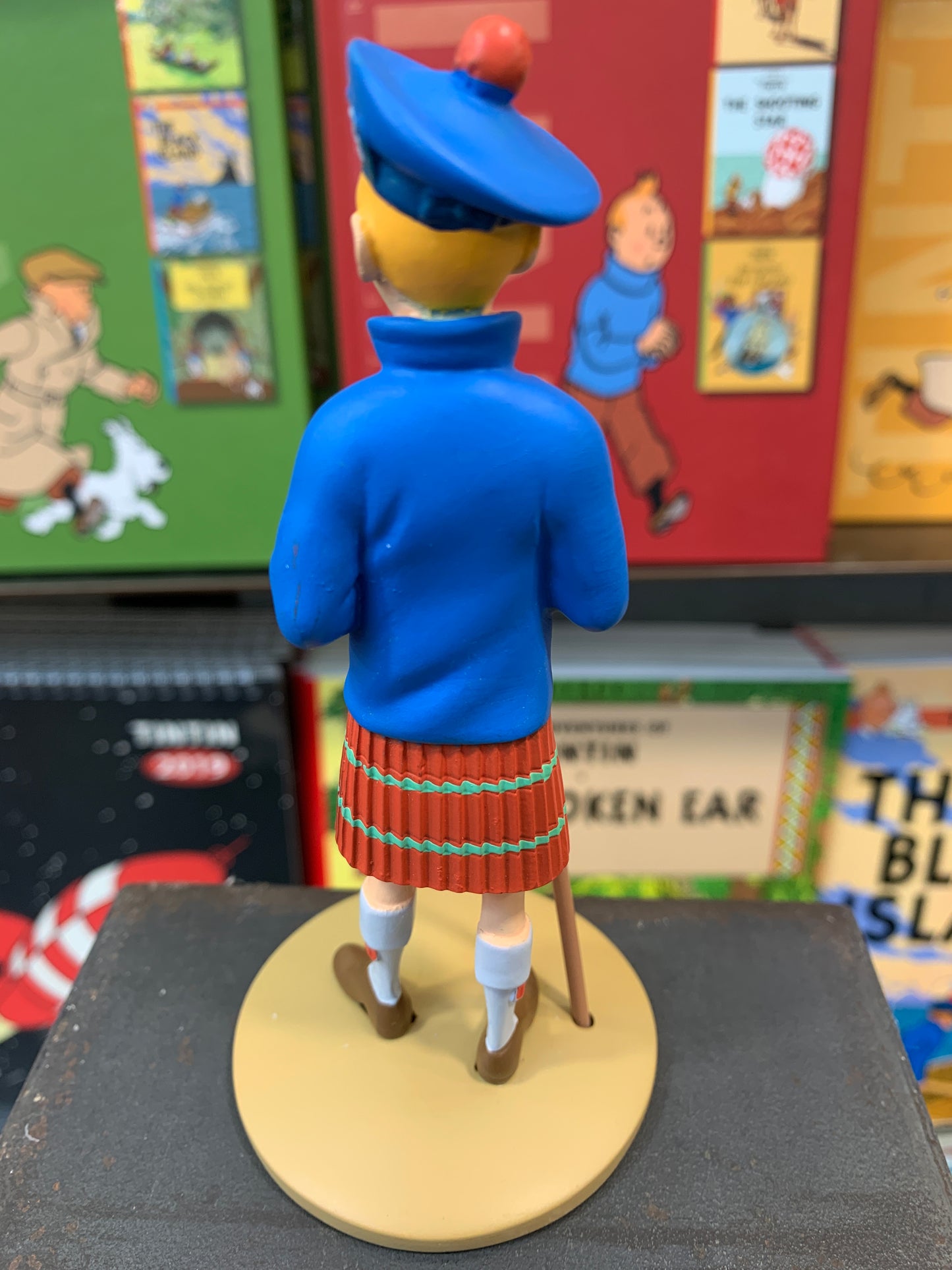 Tintin resin figure in kilt and blue sweater, from The Black Island, standing on display with Tintin books in background