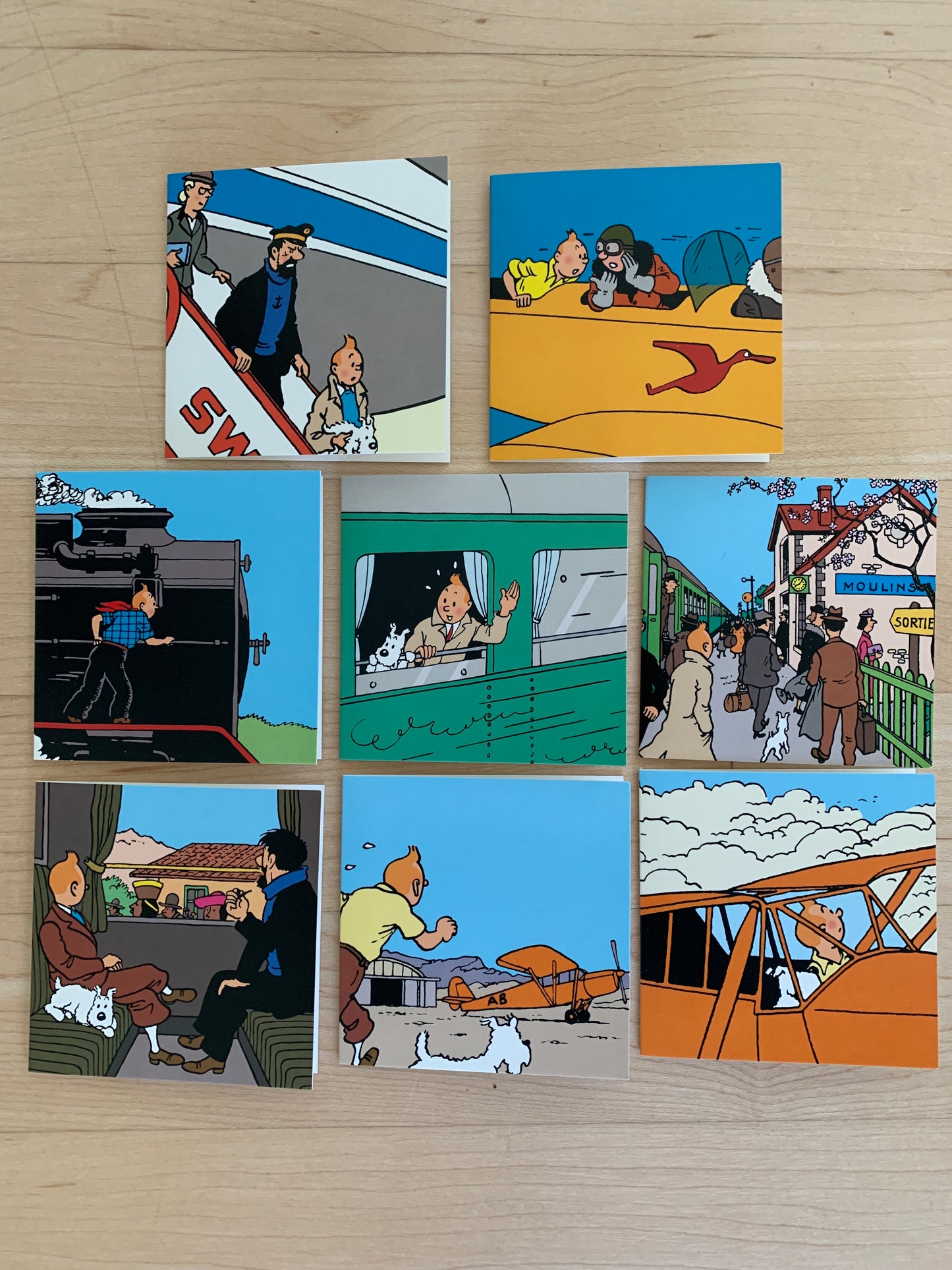 Tintin mini gift note cards featuring colorful scenes from global adventures, including trains, planes, and city streets